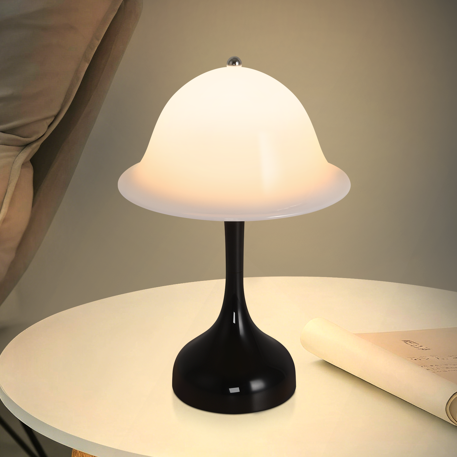 Una lampada nera con paralume bianco seduta su un tavolo accanto a un documento arrotolato.