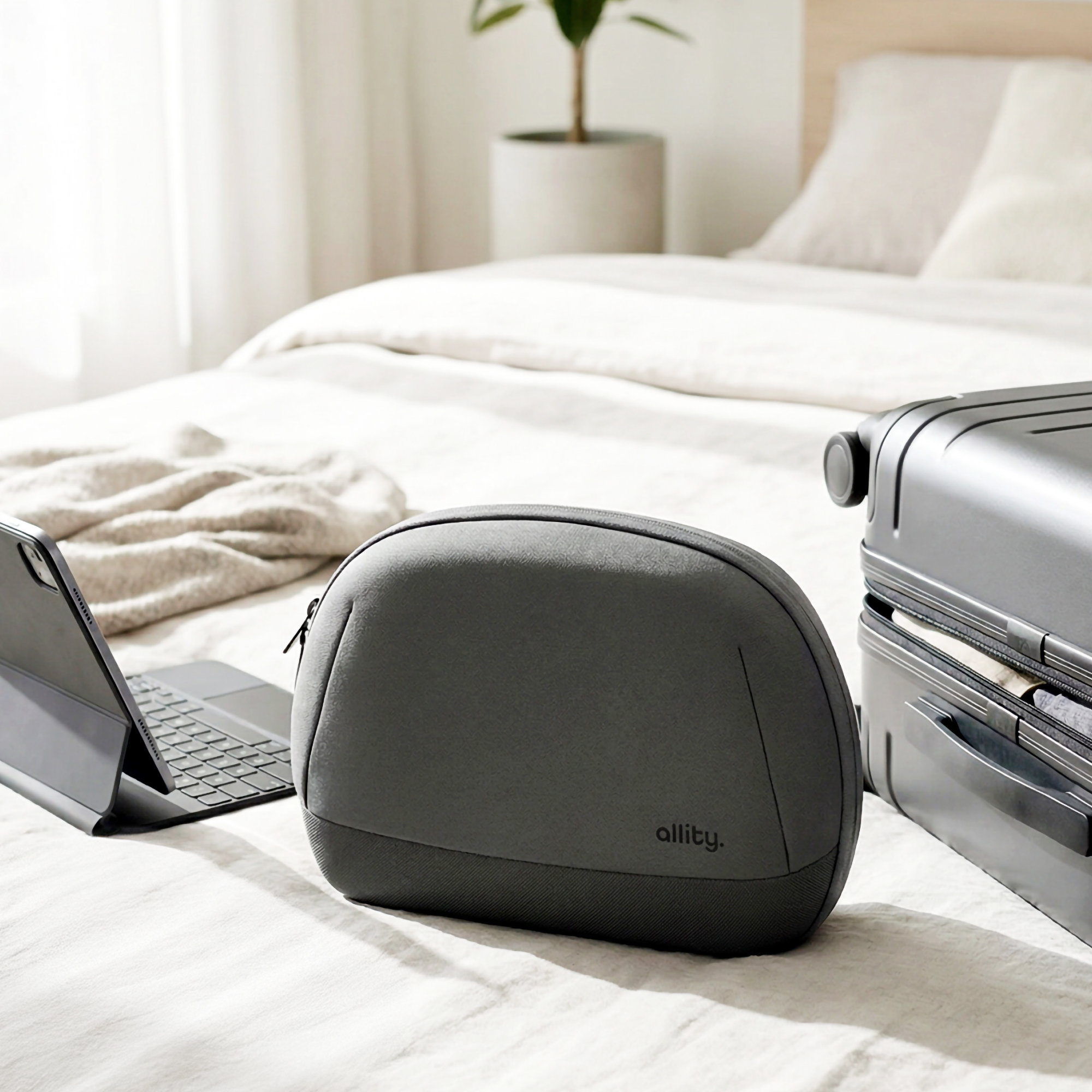 Graue Reisetasche und offener Koffer auf einem Bett mit Laptop.