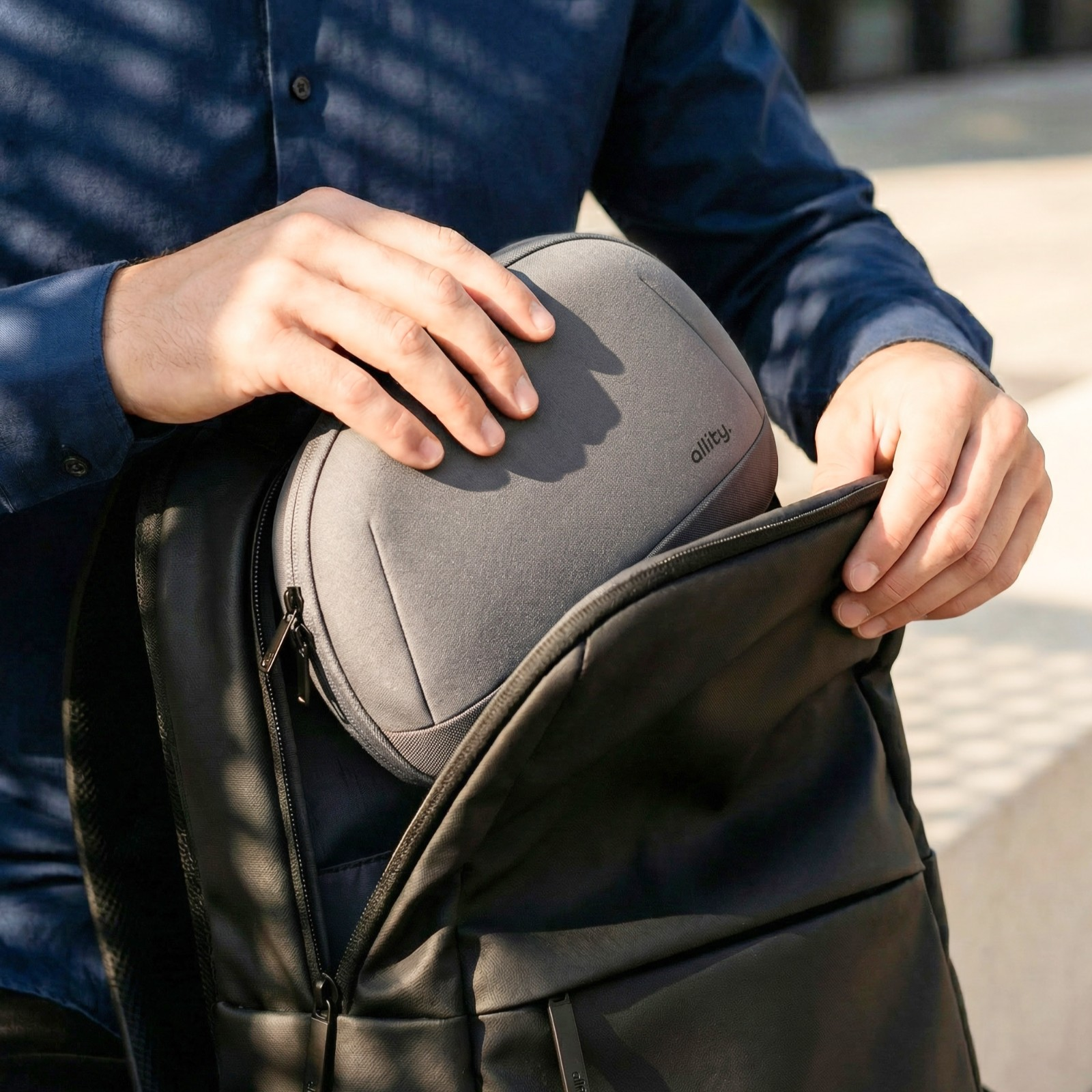 Mann packt eine graue Tasche in einen schwarzen Rucksack.