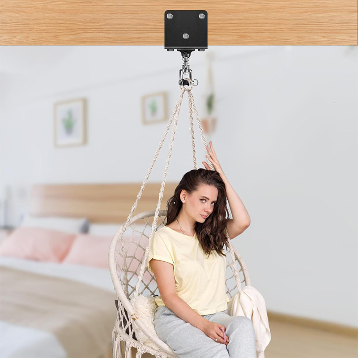 Kobieta siedzi w fotelu wiszącym przed łóżkiem.