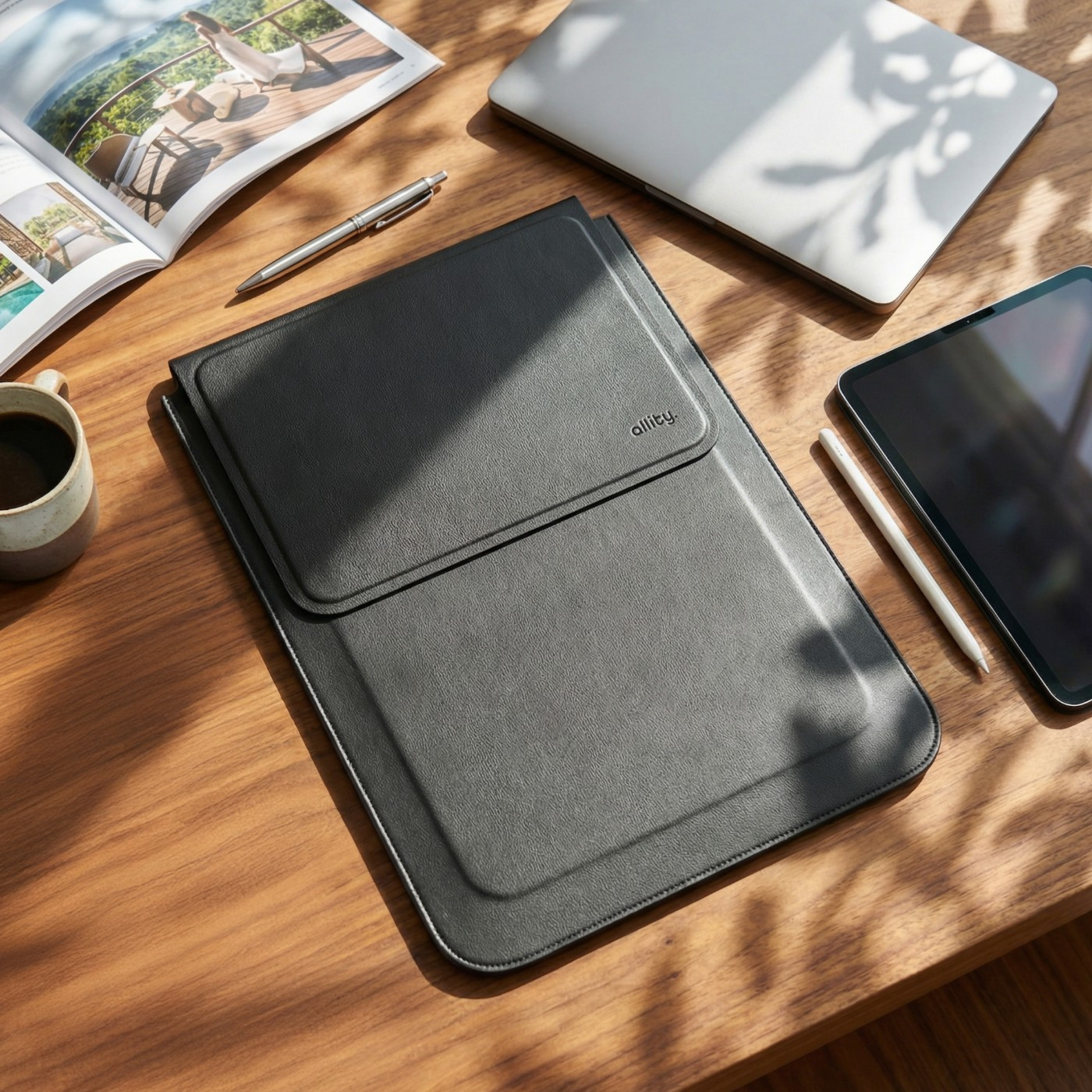 Czarny pokrowiec na laptopa, laptop, tablet i kawa na drewnianym stole.