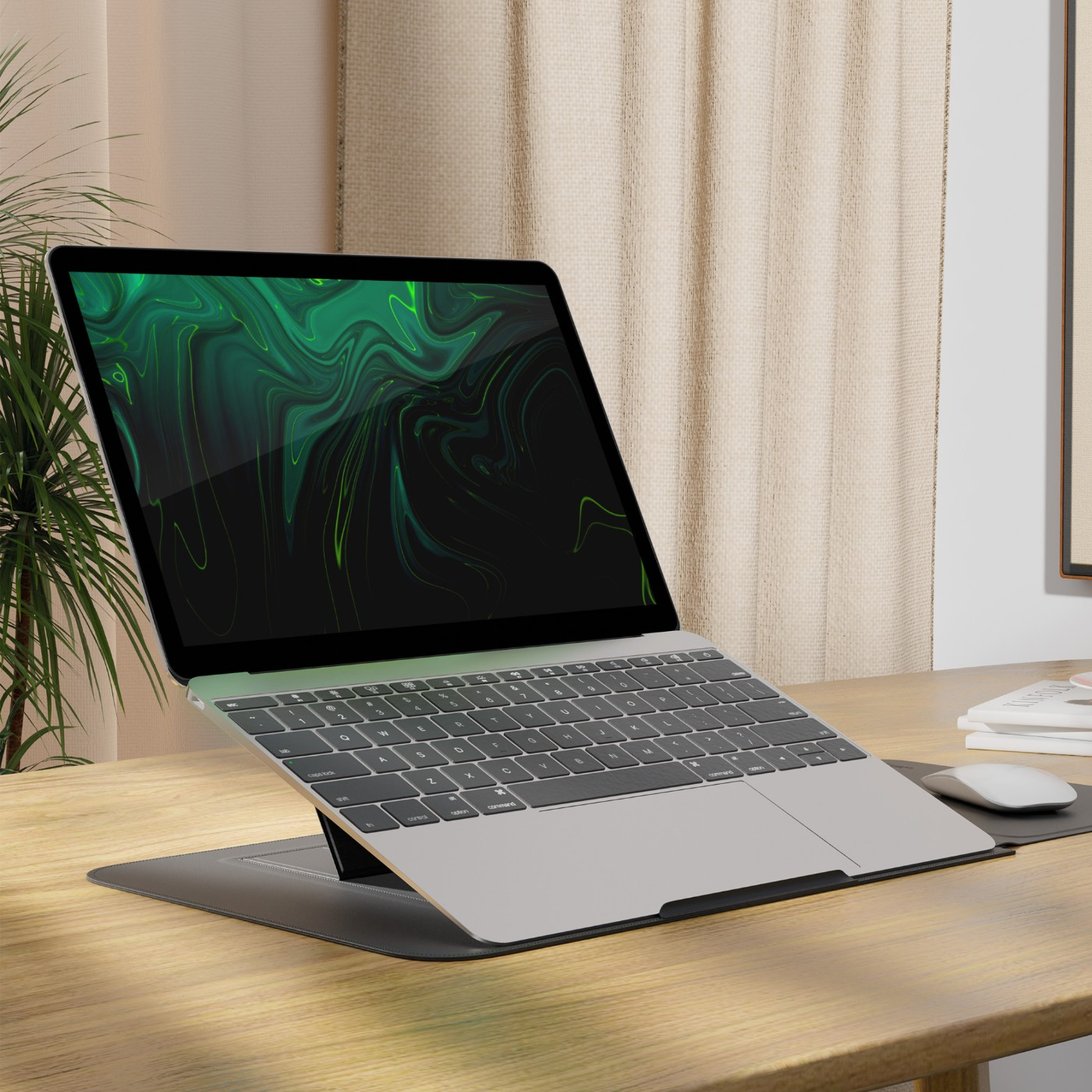 Srebrny laptop z zielną tapetą abstrakcyjną na drewnianym biurku.