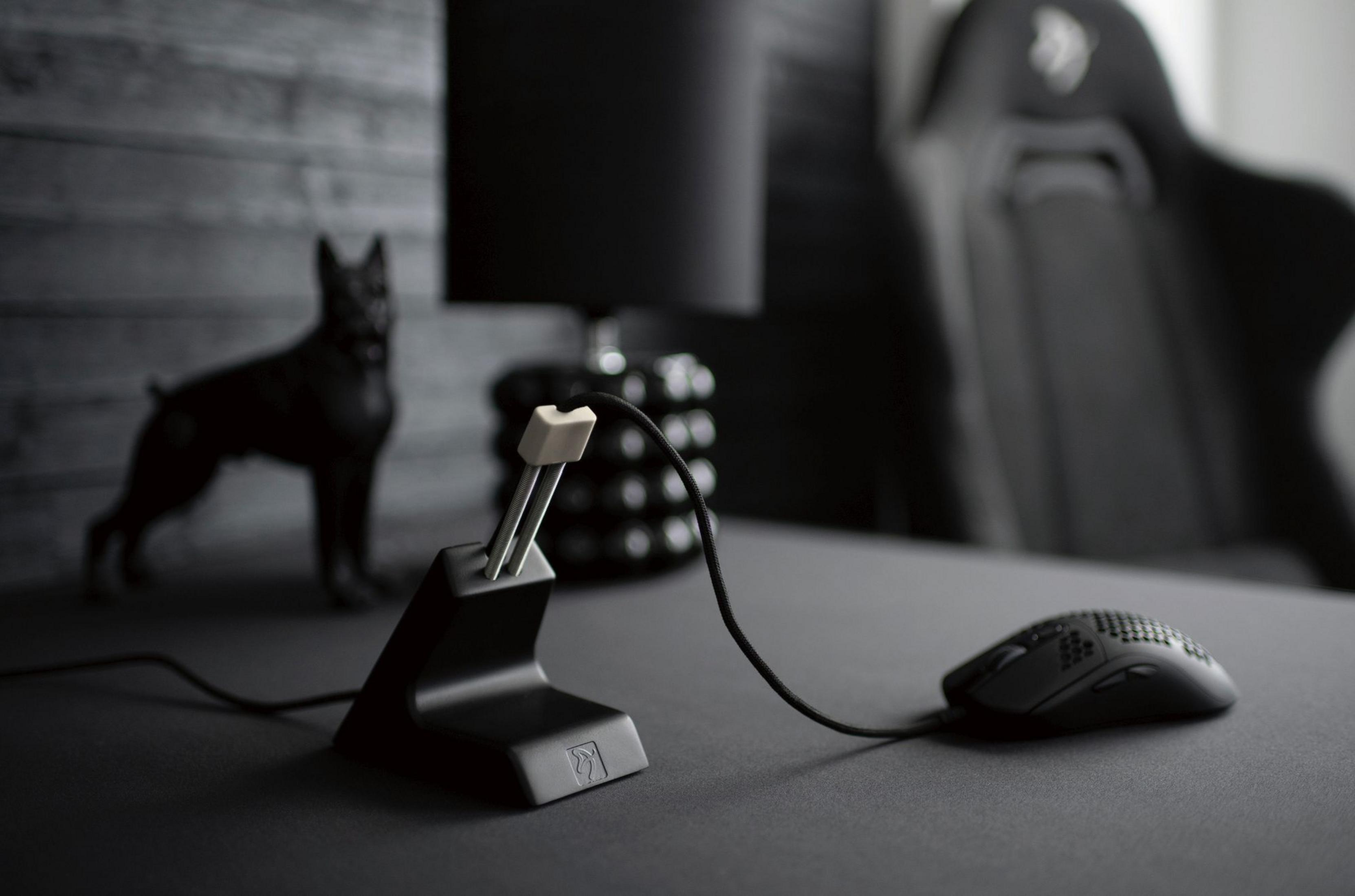 Una scrivania da gaming nera con mouse, bungee per mouse e statua di cane.