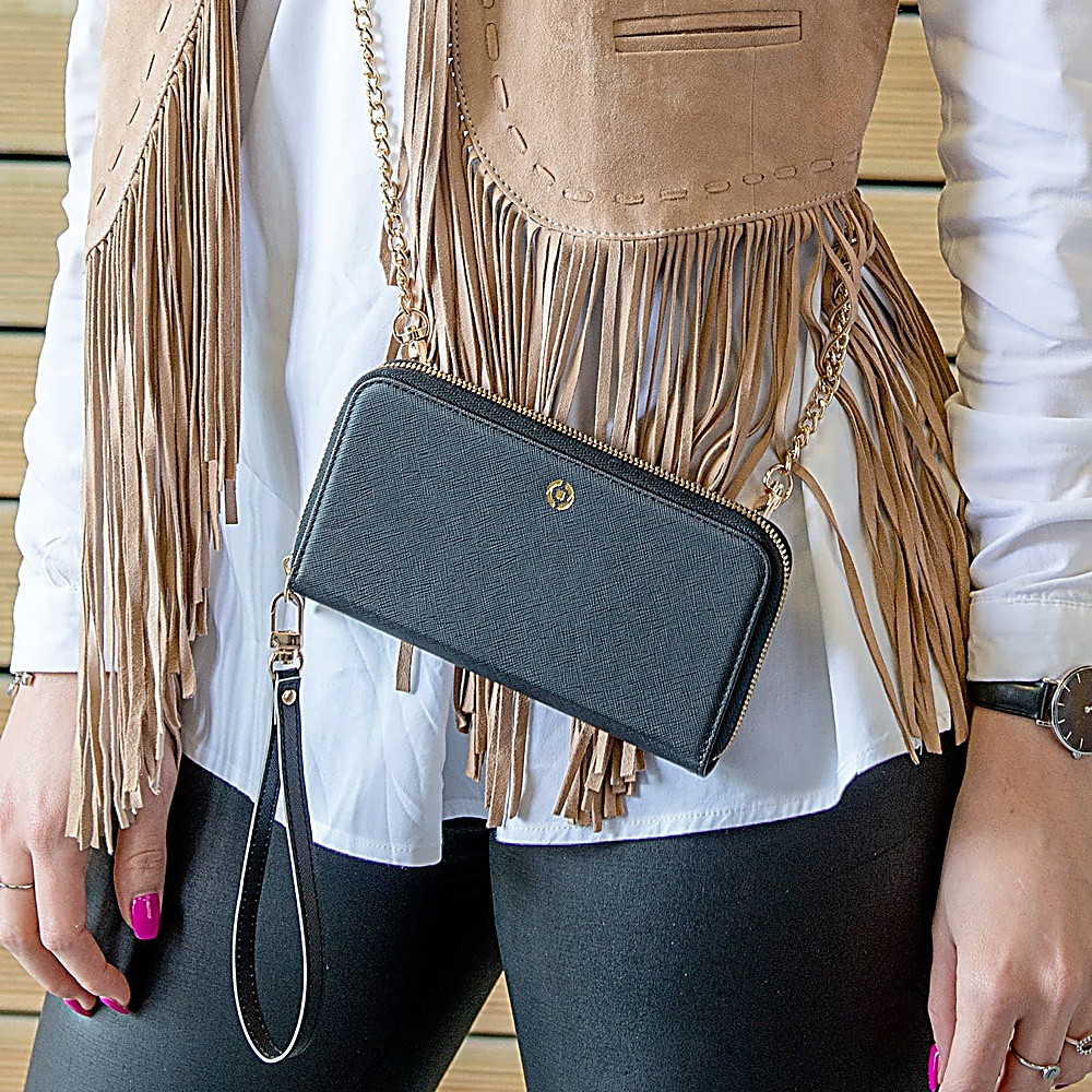 Una persona indossa una camicetta bianca, un gilet con frange e una borsa nera.