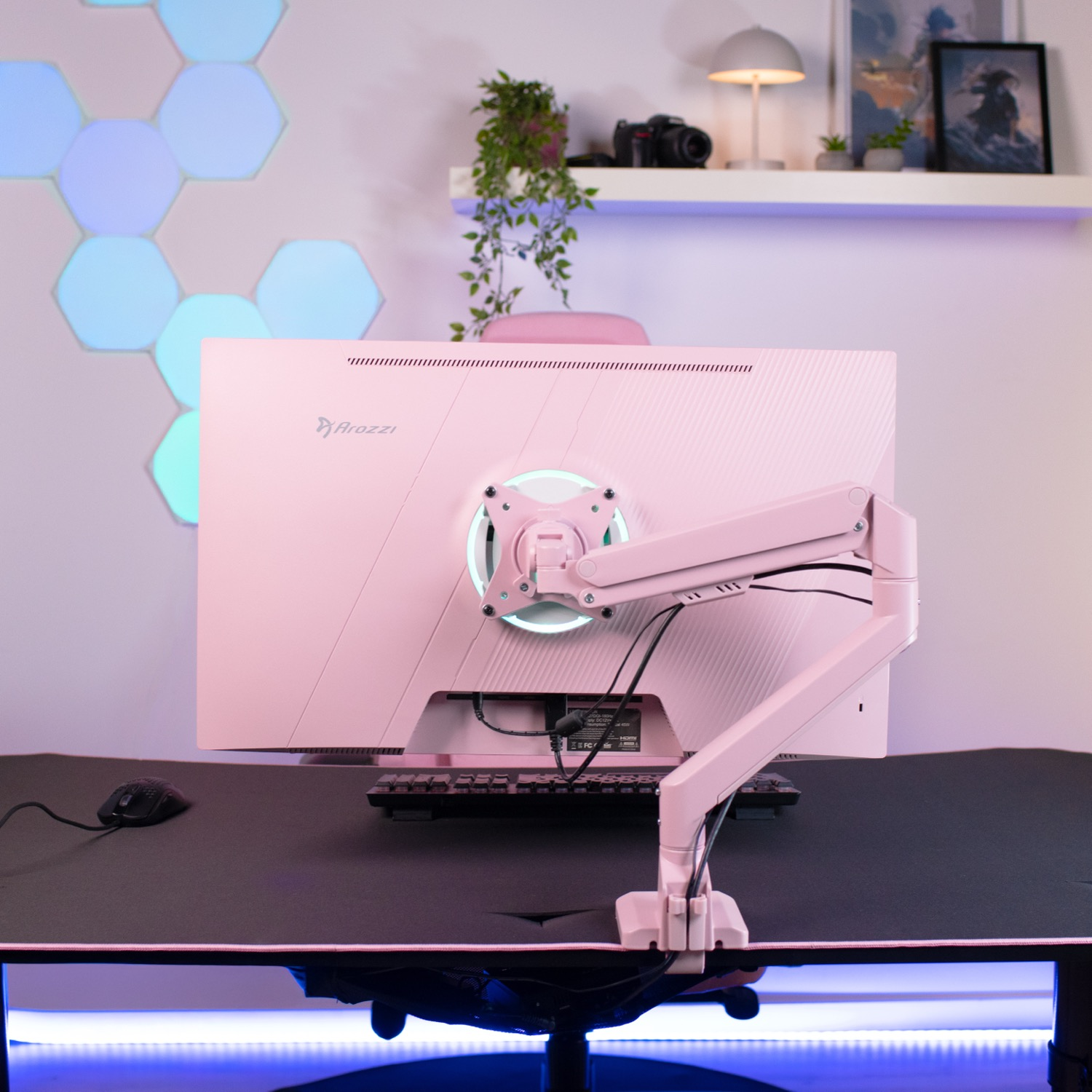 A pink monitor is mounted on a desk, with a keyboard and mouse beside it.