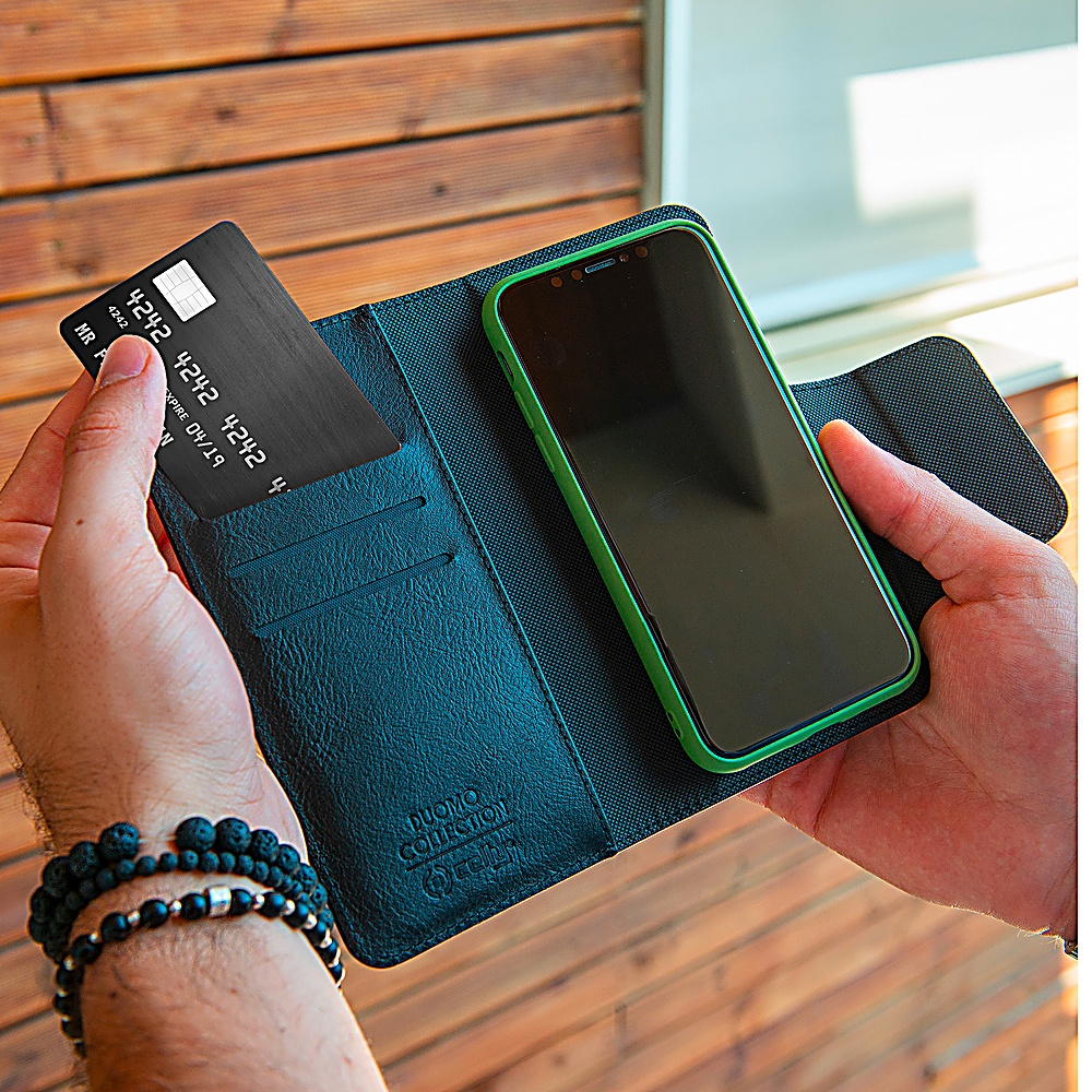 Una mano tiene una carta di credito nera accanto a uno smartphone con custodia verde.