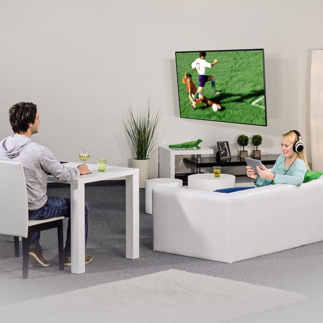 Mężczyzna przy stole, kobieta na kanapie, oglądają TV.