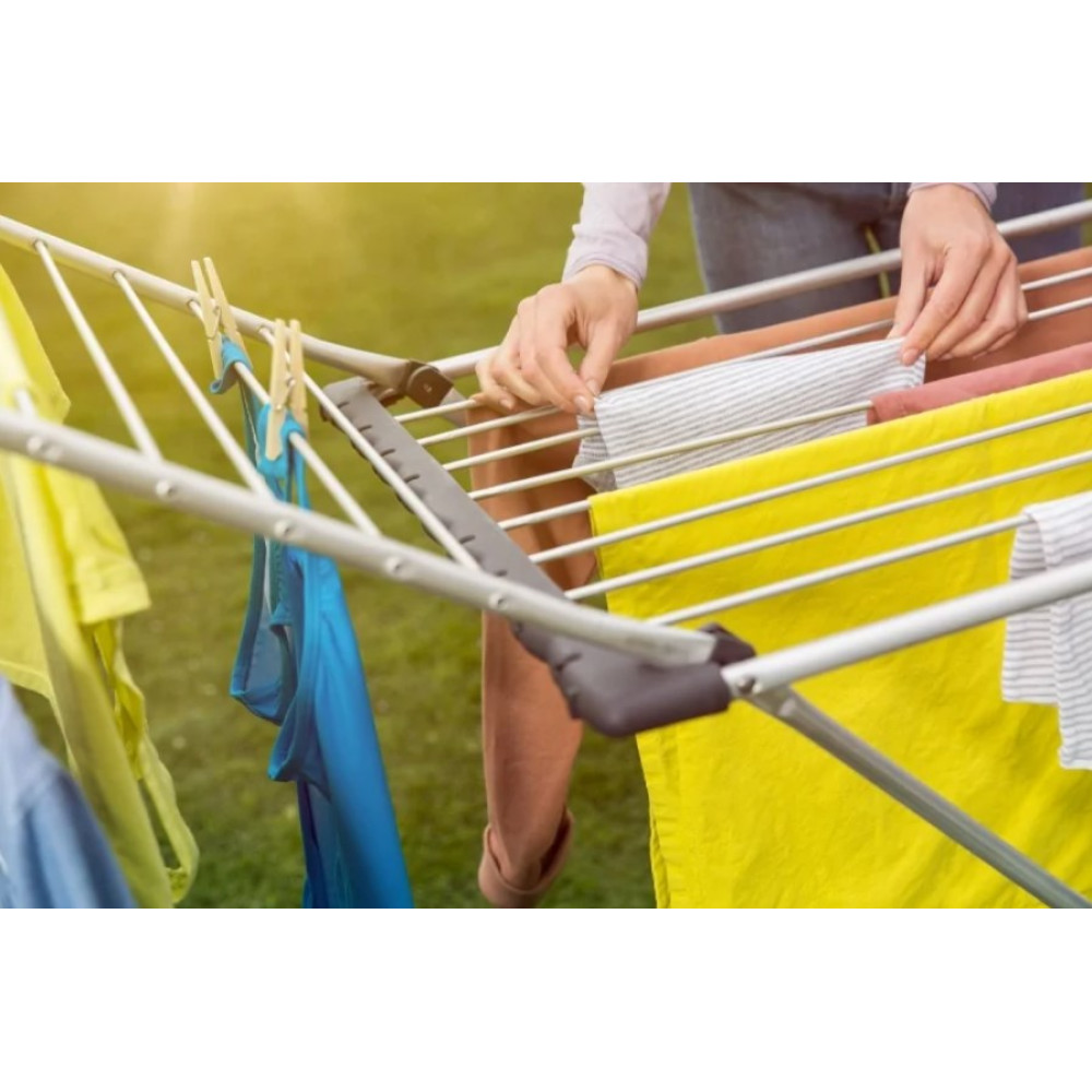 Ręce wieszają ubrania na suszarce, z żółtymi i niebieskimi rzeczami.