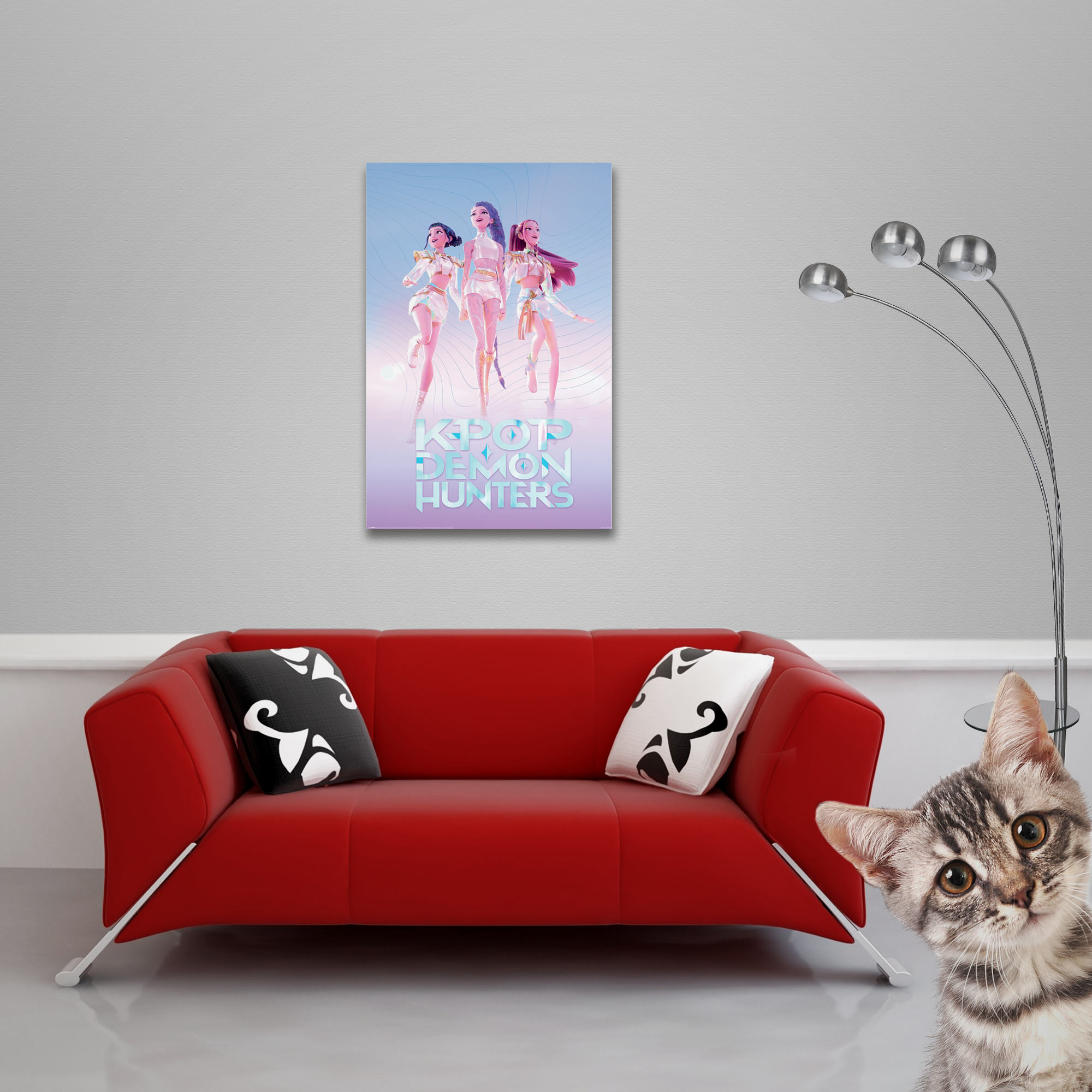 Ein Kätzchen lugt neben einer roten Couch mit Kunst hervor, die drei Anime-Charaktere zeigt.