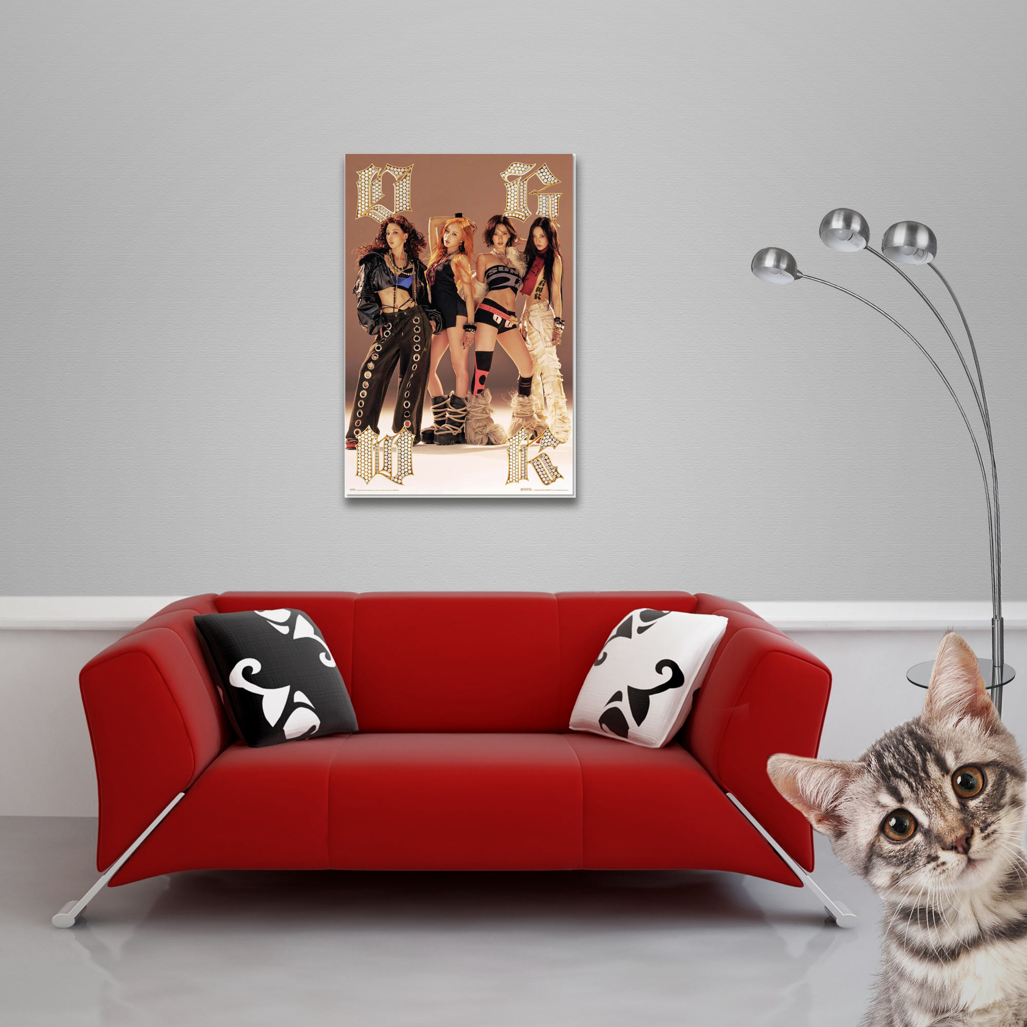 Ein Kätzchen schaut neugierig über eine rote Couch, ein Poster hängt an der Wand.