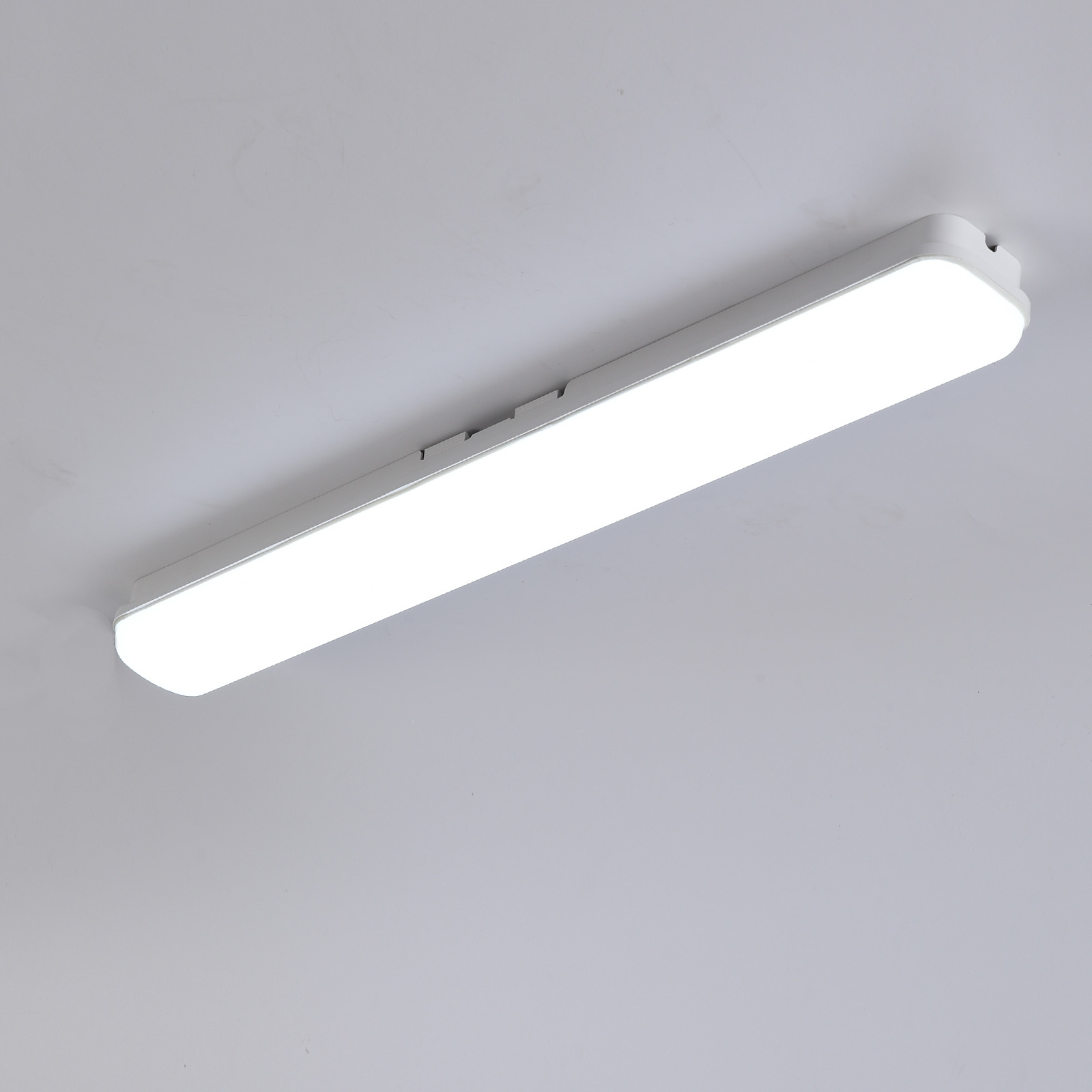 Una lámpara de techo blanca con una tira estrecha iluminada.