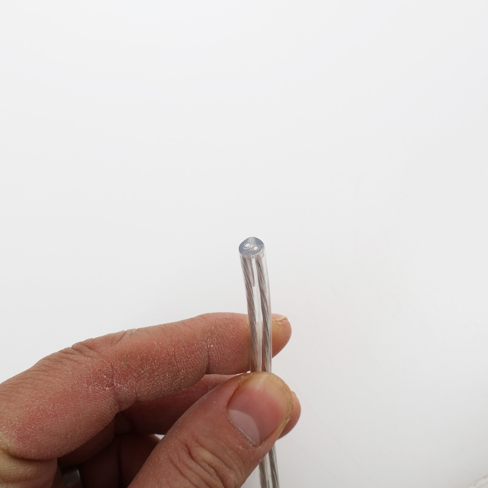 Una mano sostiene un cable transparente con tres cables.