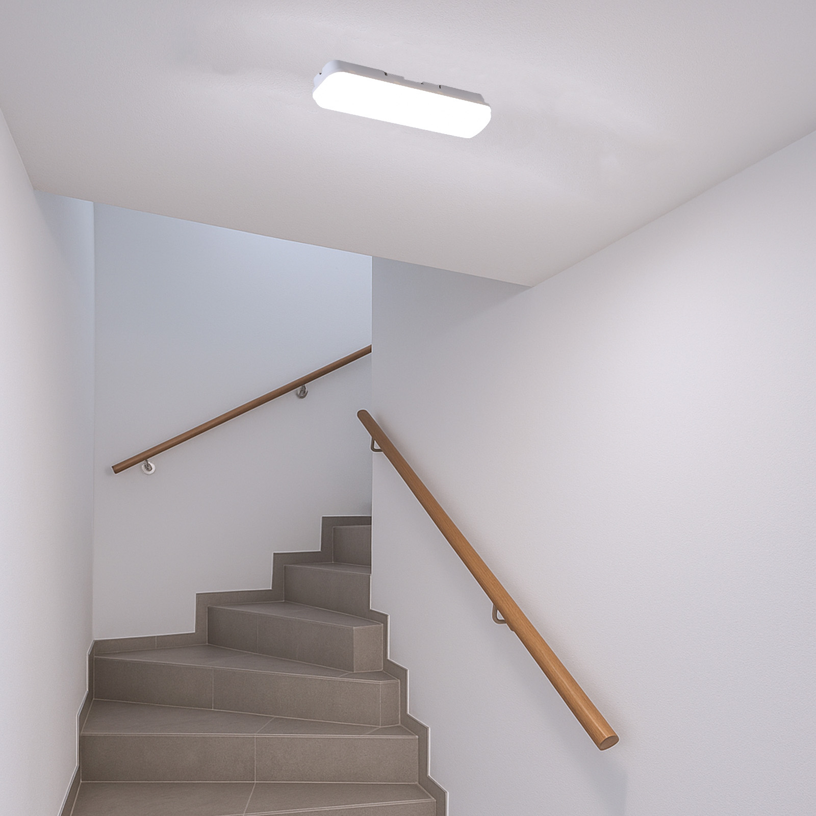 Una escalera con escalones grises, pasamanos de madera y luz de techo.