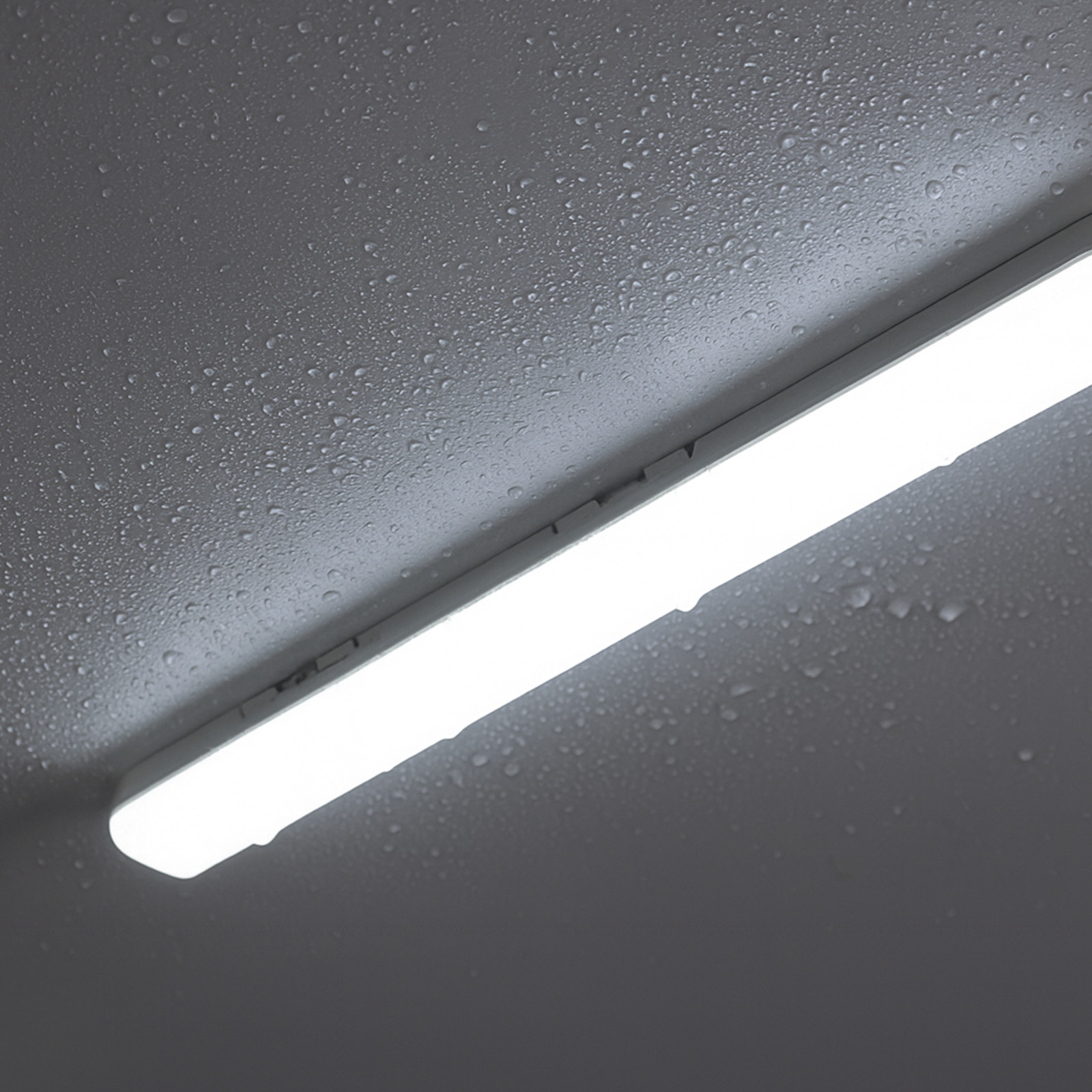 Una lámpara tubular brillante en un techo con gotas de agua.
