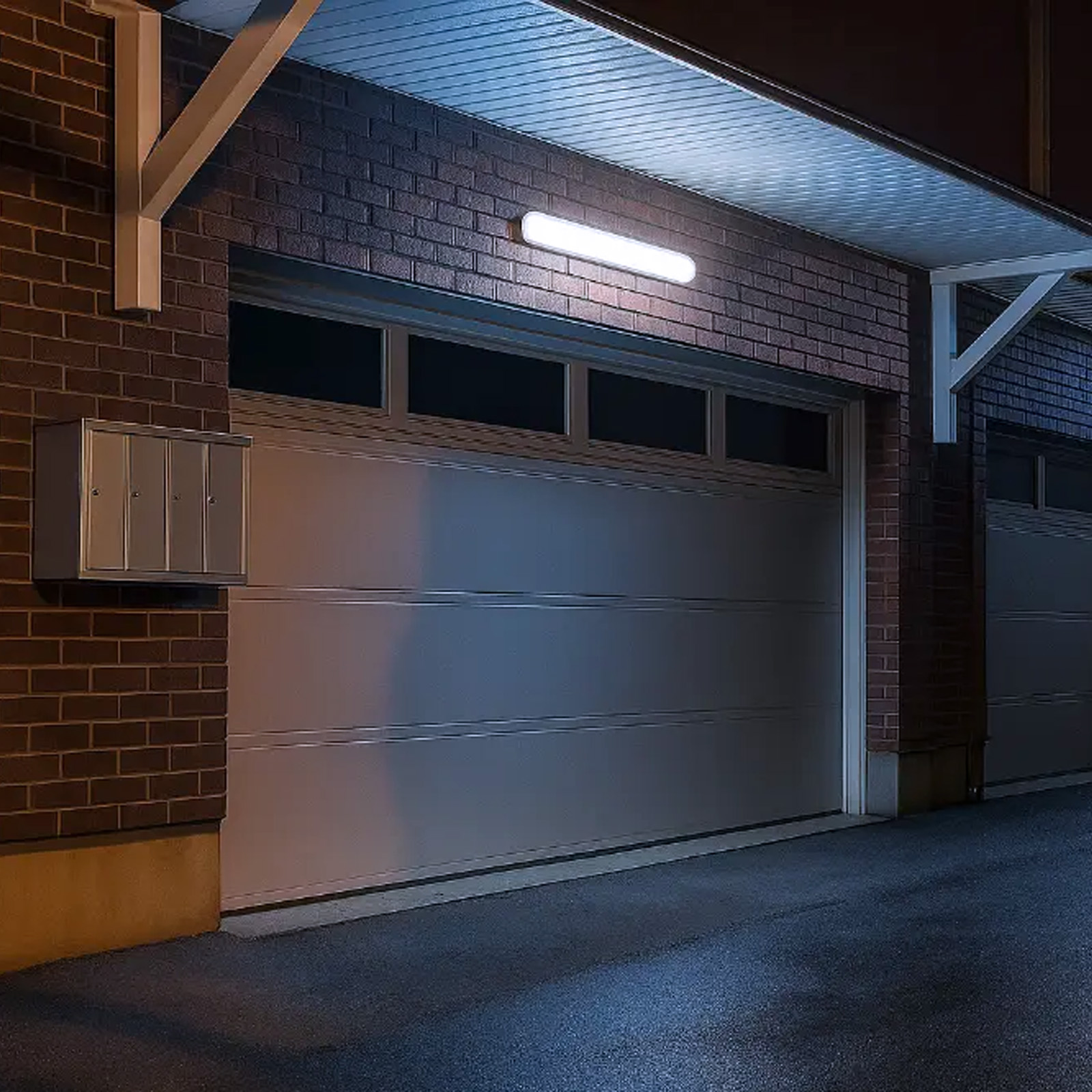 Un garaje por la noche con una lámpara brillante sobre la puerta.