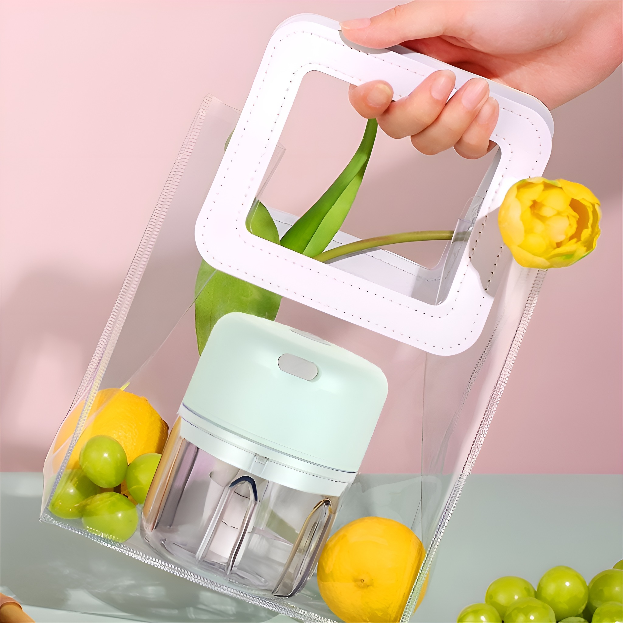 Eine Hand hält eine durchsichtige Tasche mit Obst und einem Mixer. Ein gelber Tulpenkopf ragt heraus.