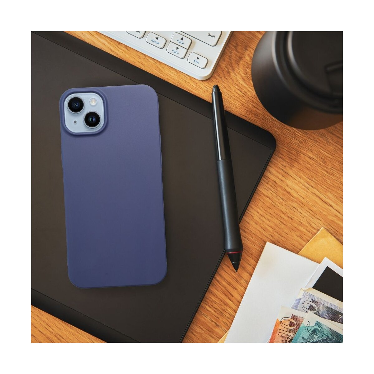 Un telefono blu su un tablet nero con penna, tastiera e denaro.