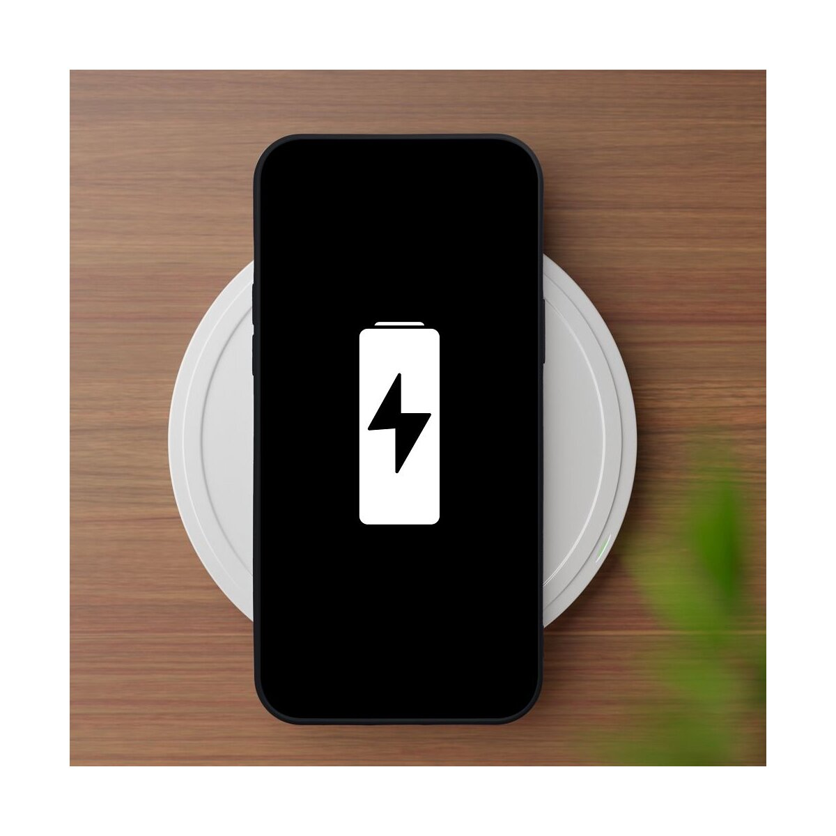 Smartphone con icona batteria scarica su pad di ricarica bianco su tavolo legno.