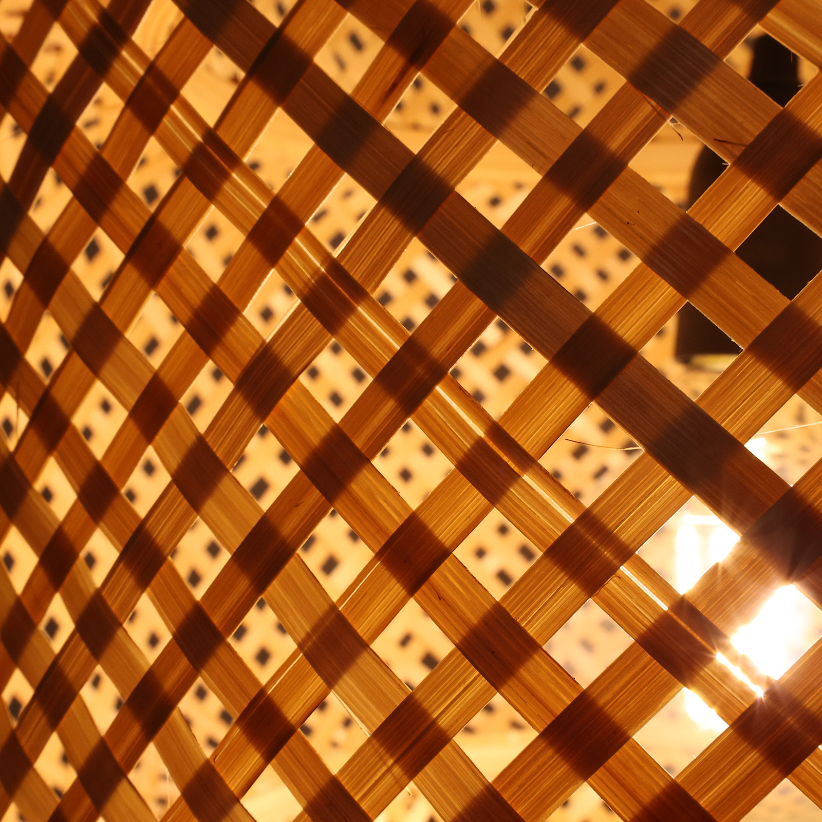 Un patrón de espiga de tiras de madera con luz cálida detrás.