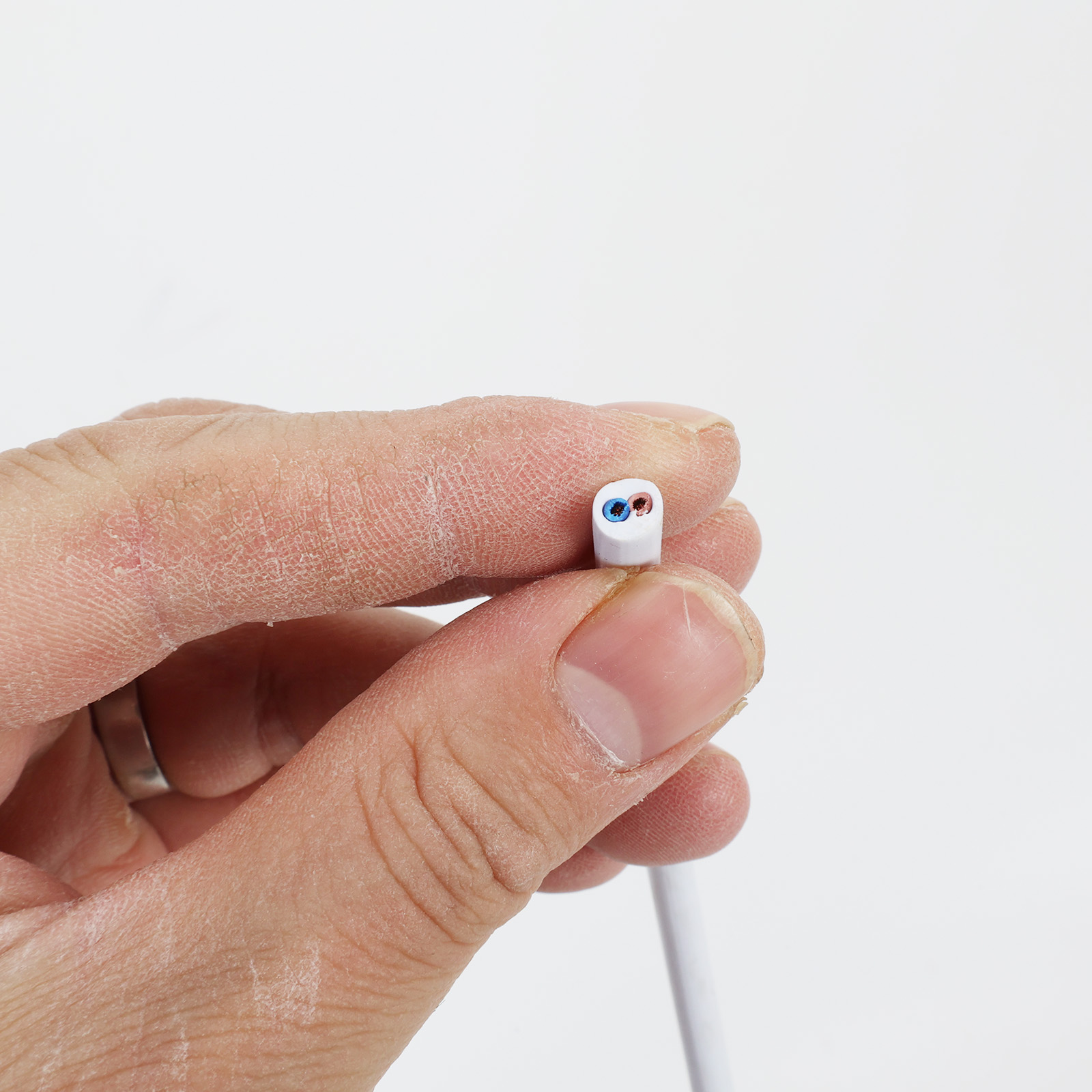 Una mano sujeta un cable blanco con dos cables expuestos: azul y rojo.