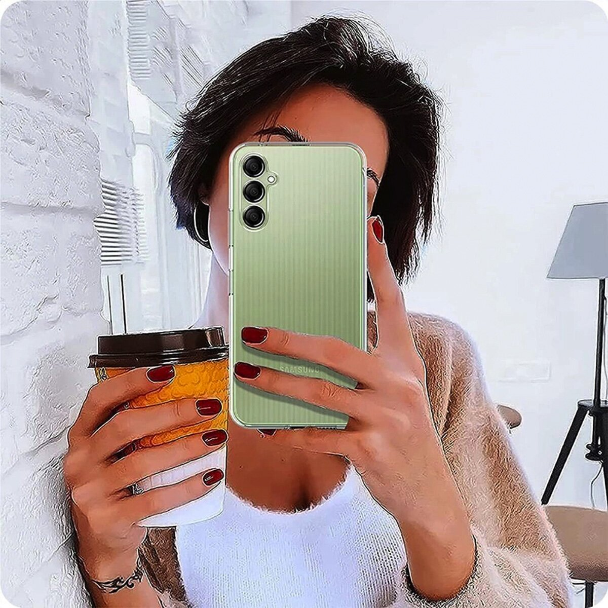 Frau mit kurzen Haaren hält eine Tasse und ein Handy mit einer Hülle.