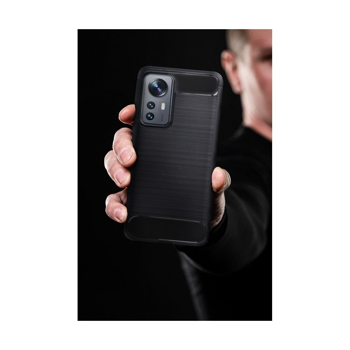 Un uomo tiene un telefono cellulare nero con un complesso sistema di fotocamere.