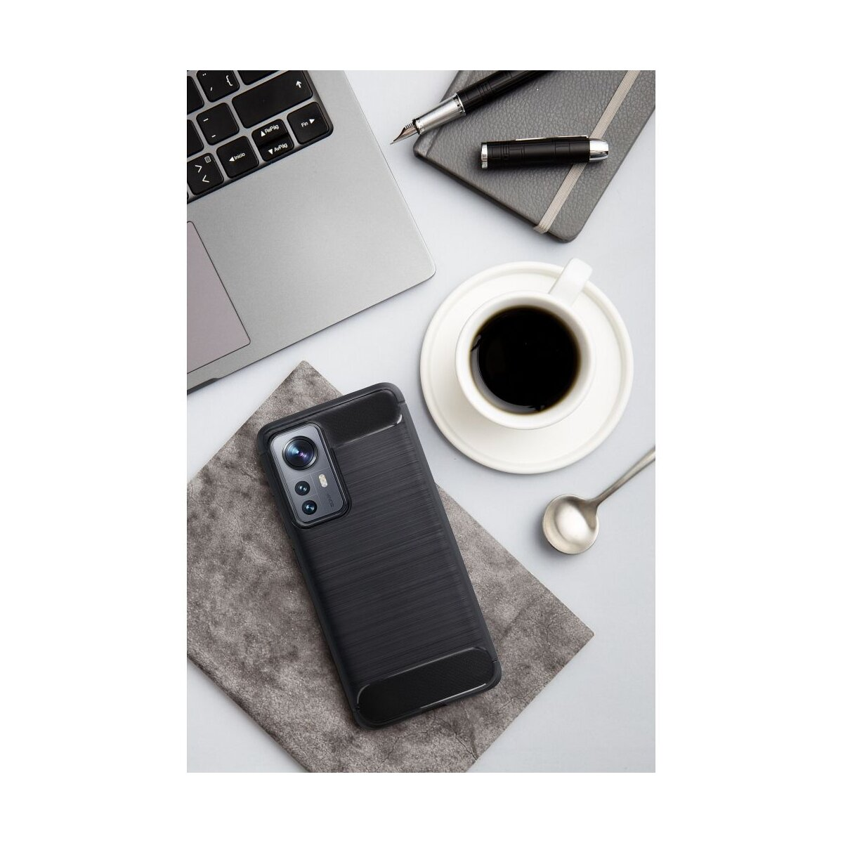 Een smartphone met zwarte hoes ligt op een grijze doek naast een koffiekopje.