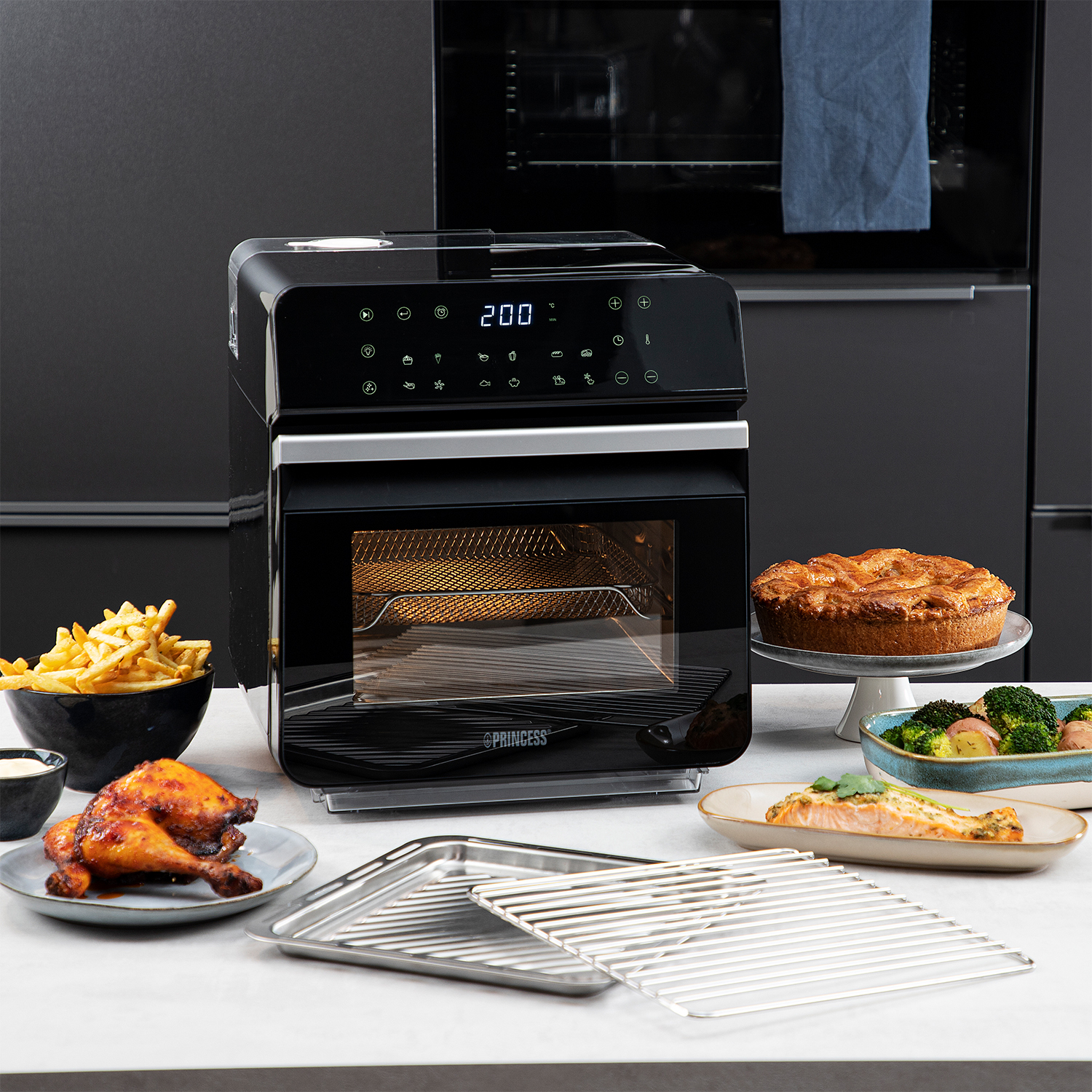 Un forno friggitrice ad aria nero con cibi cotti come pollo e pesce.