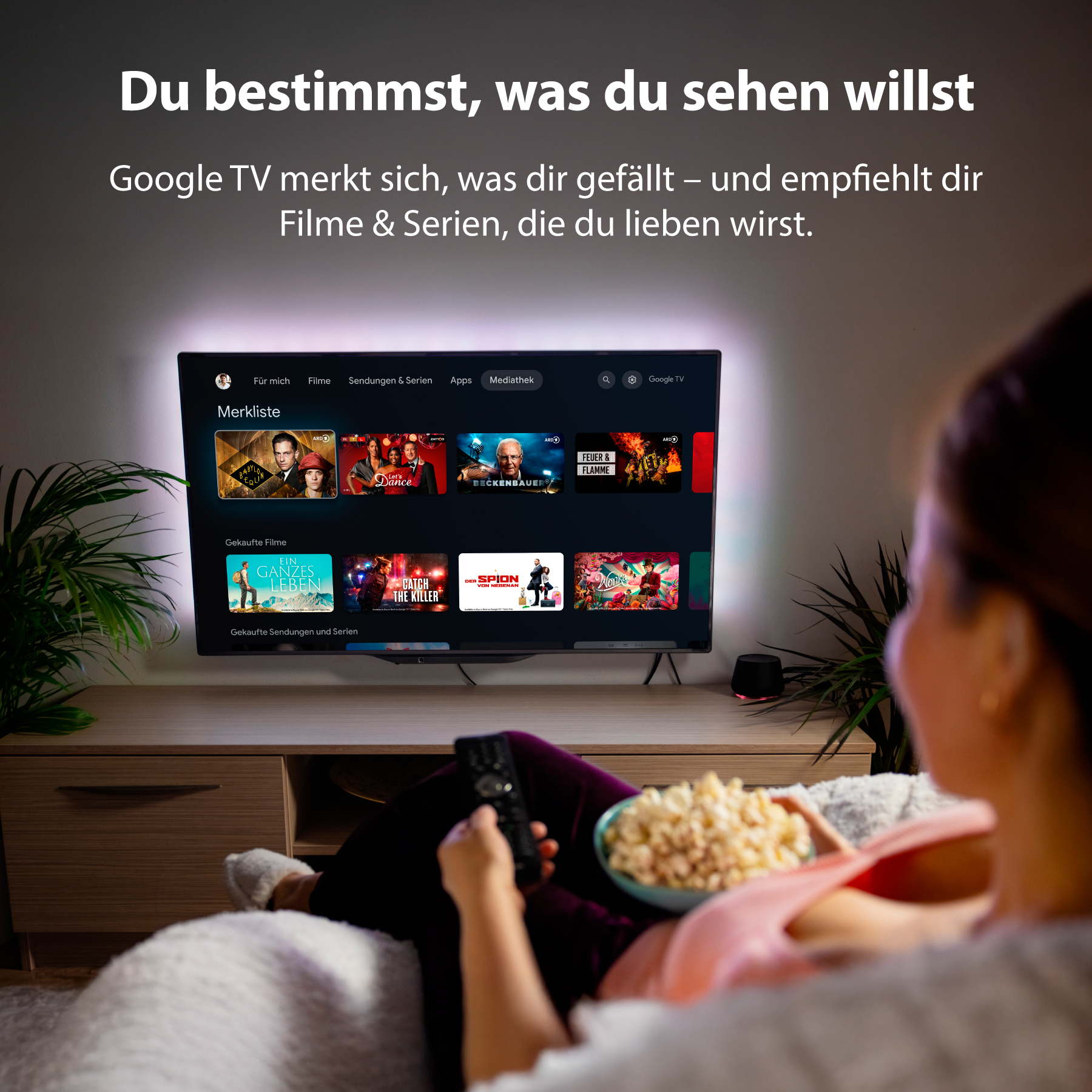 Person schaut TV mit Popcorn. Der Bildschirm zeigt Google TV mit Filmen.