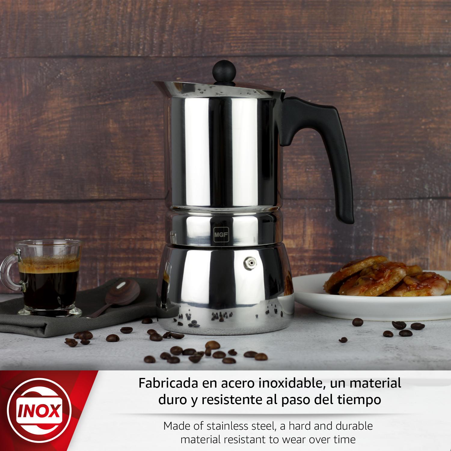 Cafetera de acero inoxidable con espresso, granos y pasteles sobre fondo de madera.
