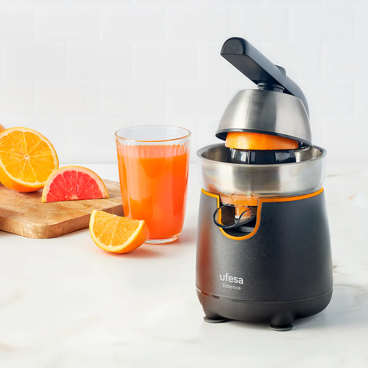 Spremiagrumi elettrico con mezza arancia, mezzo pompelmo e bicchiere di succo.
