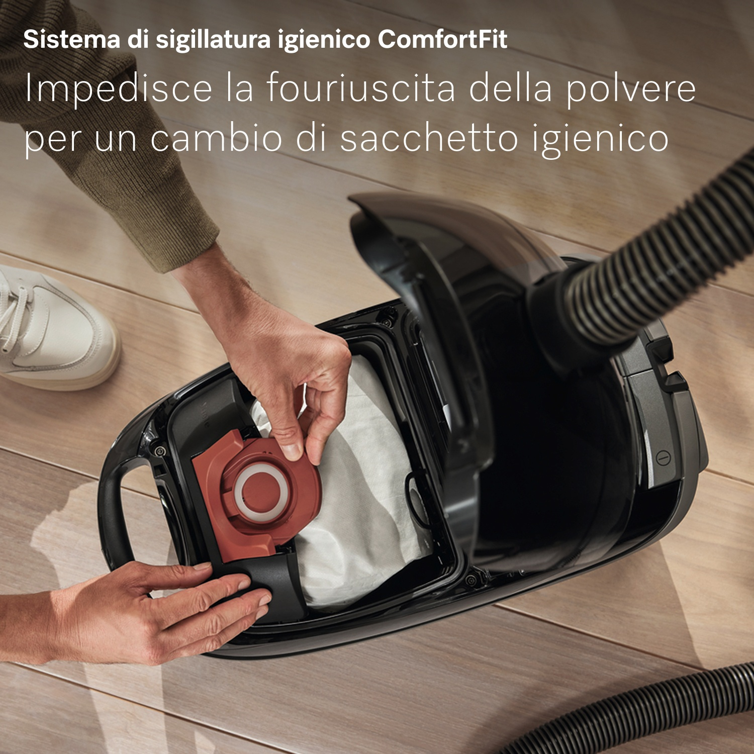 Mani inseriscono porta sacchetto rosso in aspirapolvere nero.