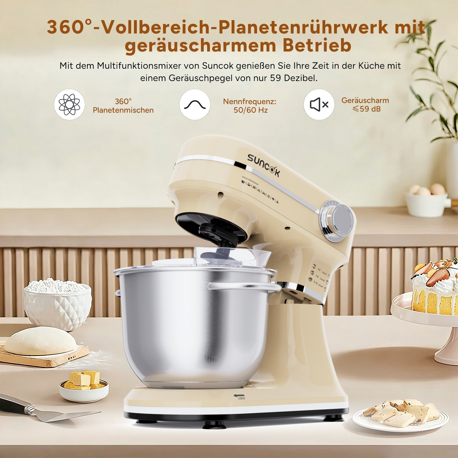 Eine cremefarbene Küchenmaschine mit Edelstahlschüssel, Teig, Butter, Kuchen und Keksen.