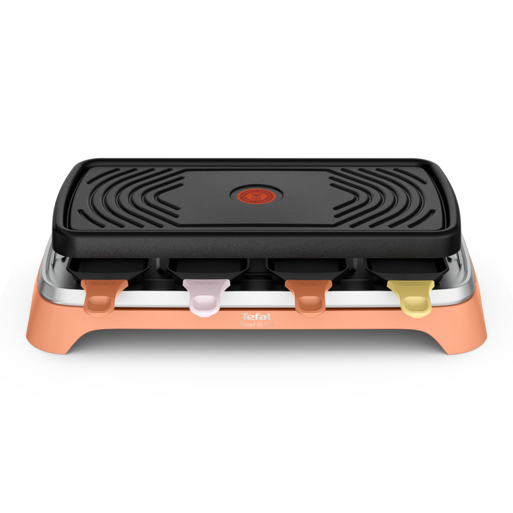 Ein orangefarbener Raclettegrill mit schwarzer Platte und vier Schiebern in Rosa, Orange und Gelb.