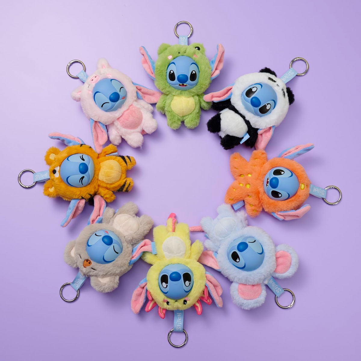 Un círculo de 8 peluches de Stitch con disfraces de animales sobre fondo morado.