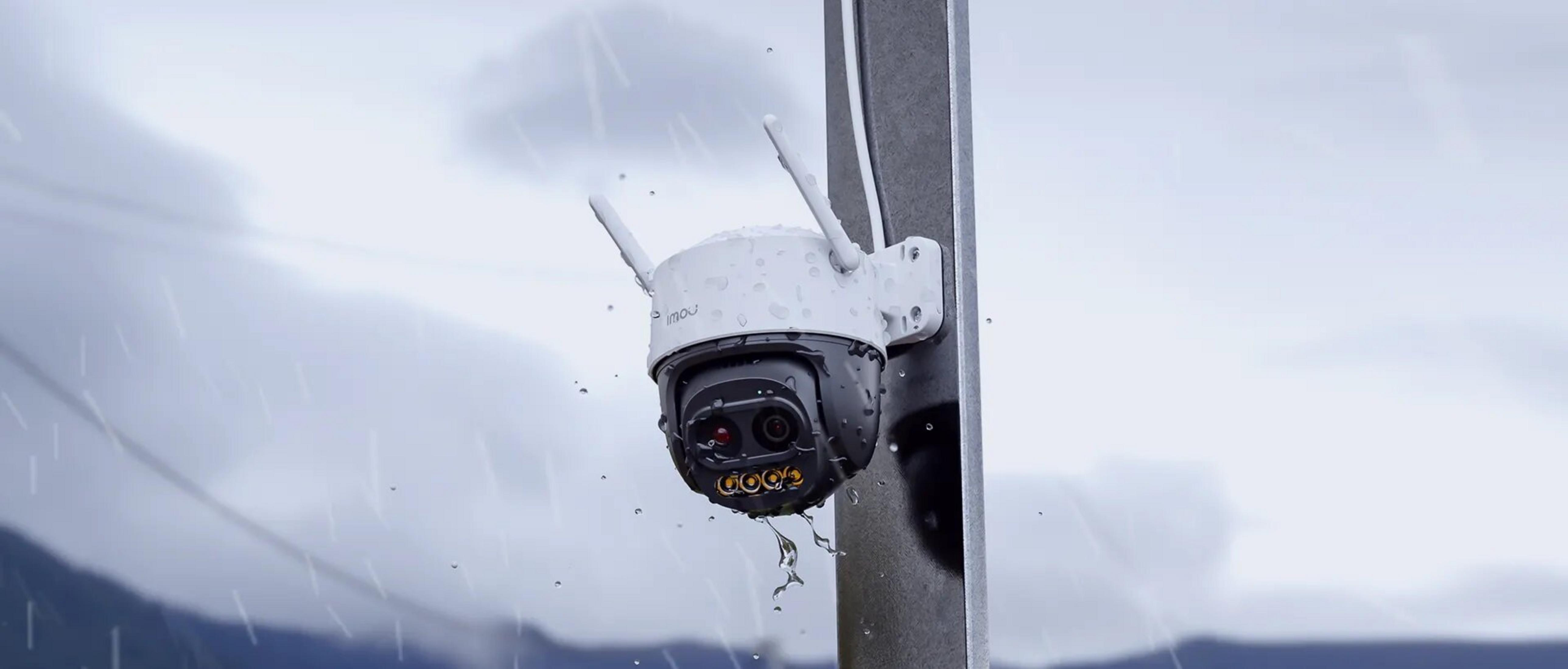 A surveillance camera with antennas mounted on a pole in the rain.