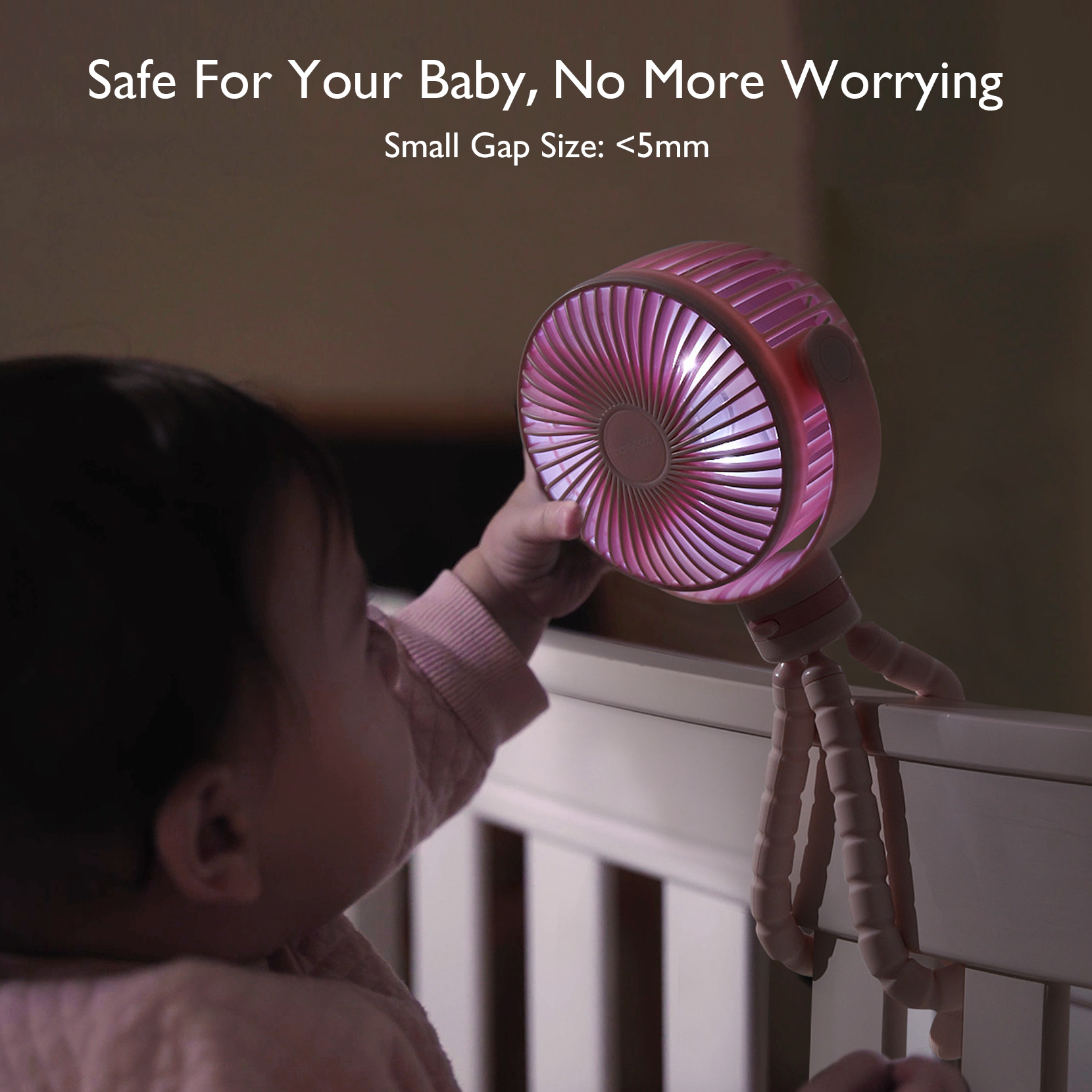 Ein Baby berührt einen rosa Ventilator mit Flex-Arm, der am Babybett befestigt ist.