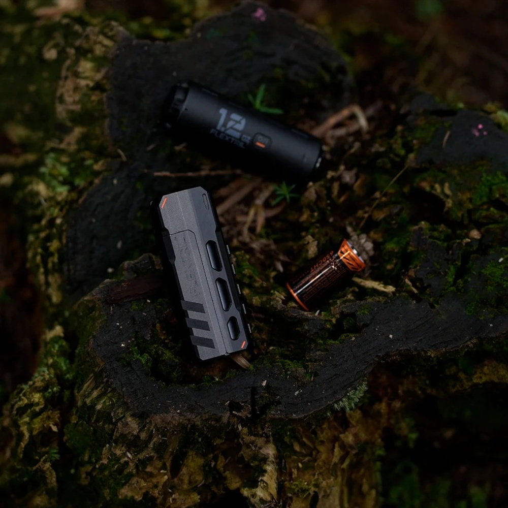 Zwei schwarze Taschenlampen und eine Batterie liegen auf moosbewachsenem Holz.