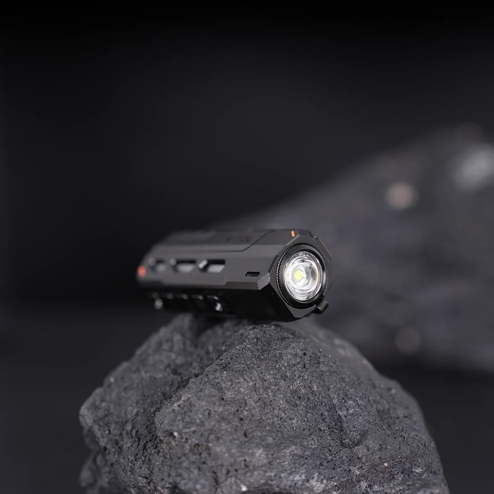 Eine schwarze Taschenlampe mit Lüftungsschlitzen auf einem dunklen Stein.