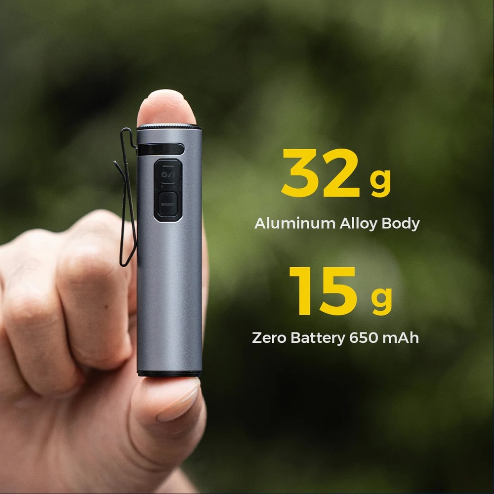 Ein graues zylindrisches Gerät mit Clip wird zwischen Daumen und Zeigefinger gehalten. Text besagt 32g Aluminiumlegierung Körper und 15g Zero Batterie 650 mAh.