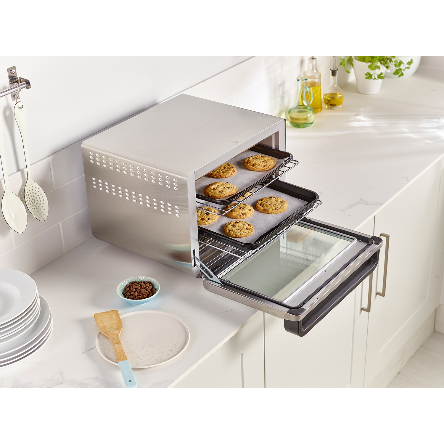 Ein silberner Toaster-Ofen mit gebackenen Keksen auf zwei Ebenen steht auf einer Arbeitsplatte.