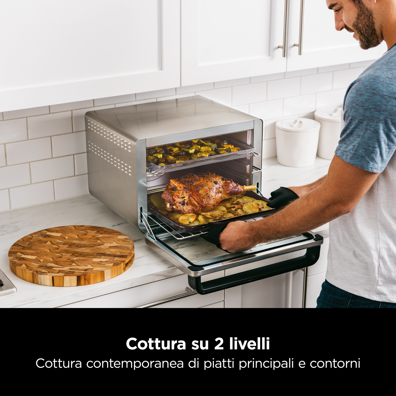 Mann entnimmt Braten und Kartoffeln aus einem silbernen Ofen mit zwei Ebenen.