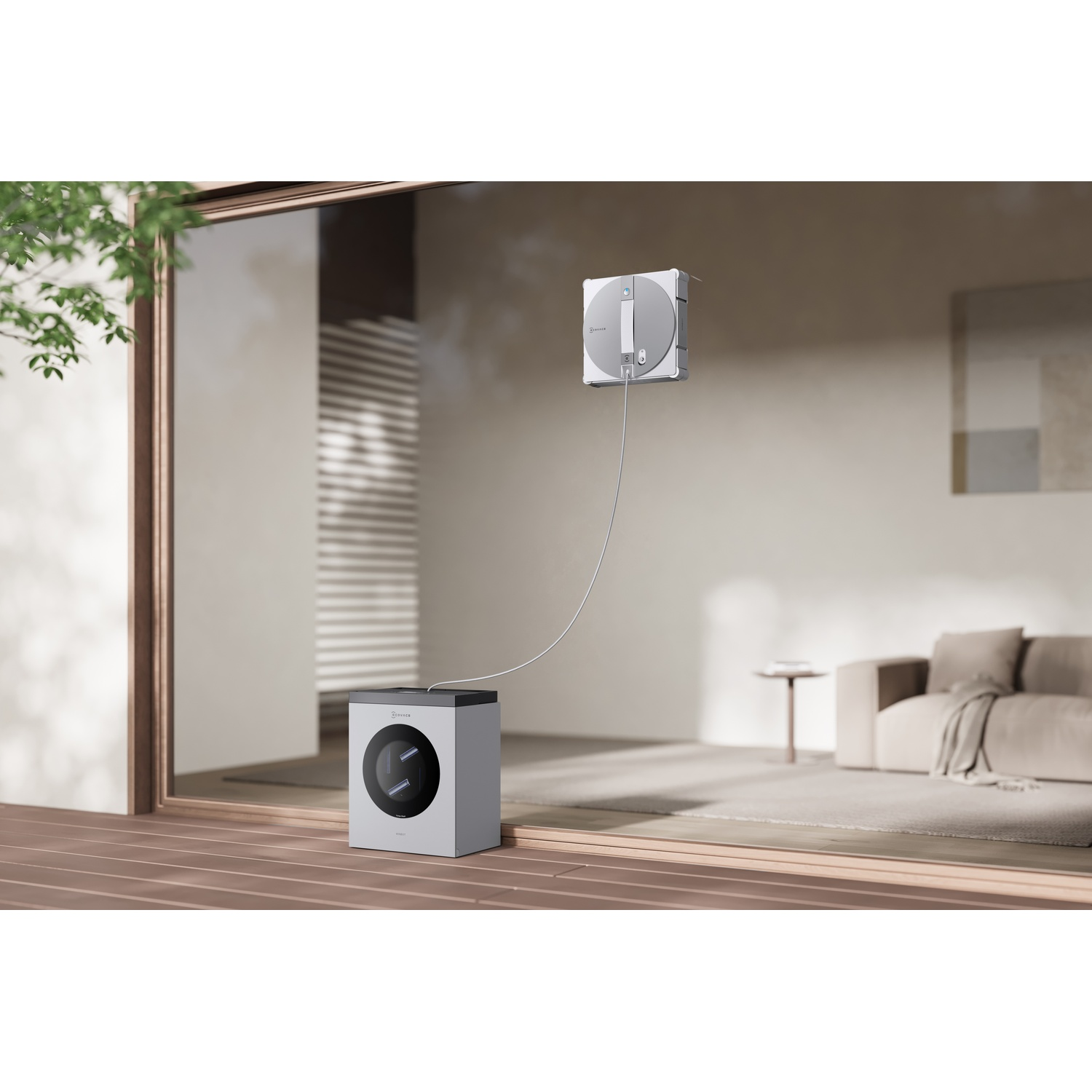 Ein Roboter reinigt ein Fenster, verbunden mit einer Basisstation draußen.