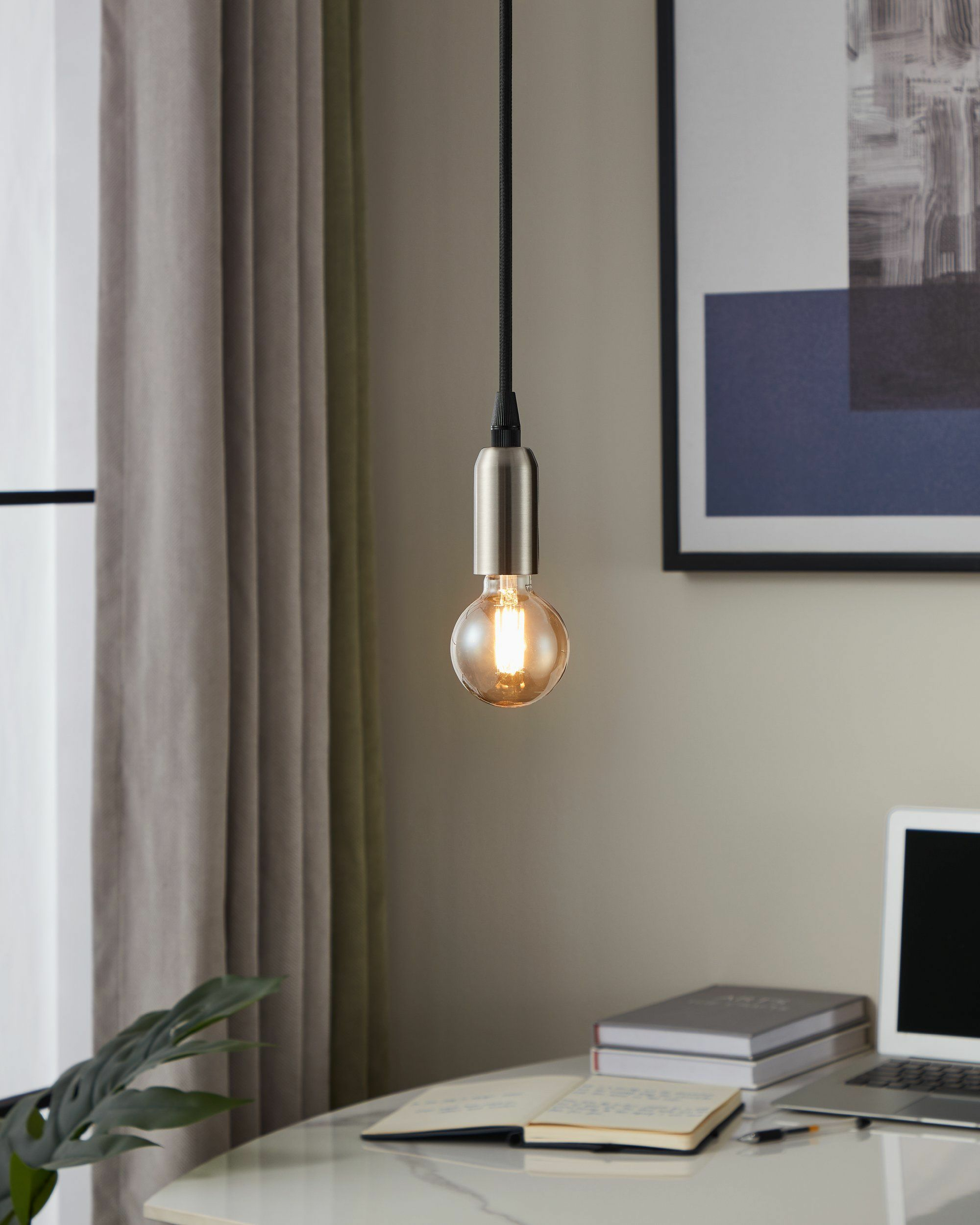 Ampoule suspendue au-dessus d'un bureau avec ordinateur portable et livres.