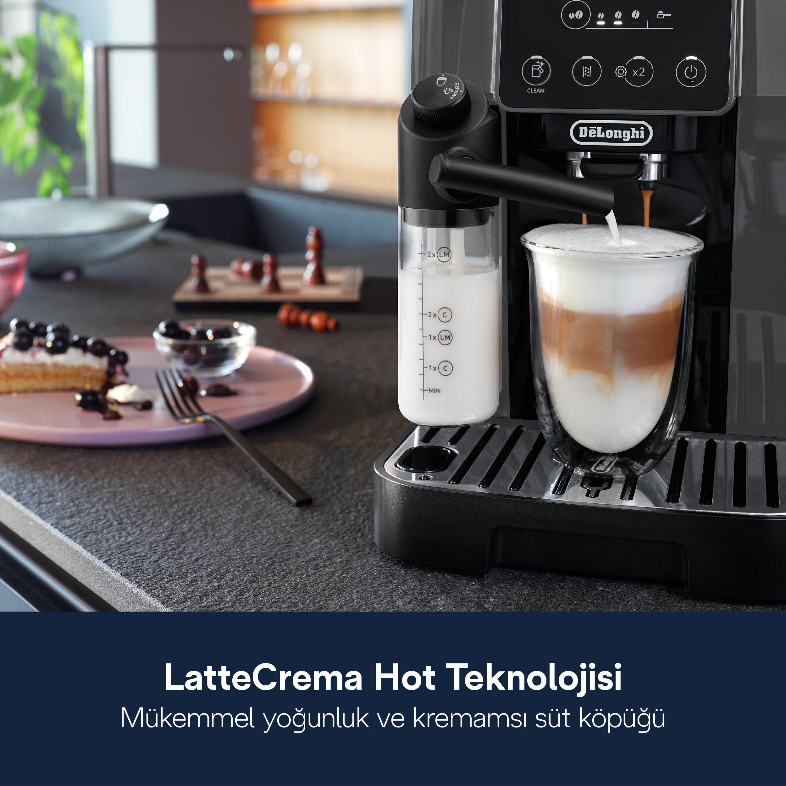 Una macchina da caffè prepara un latte, accanto c'è una torta con frutti di bosco.