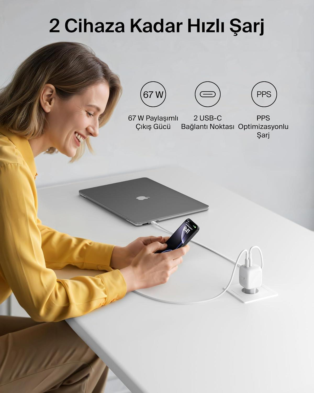 Una donna carica un iPhone e un laptop con un caricatore bianco.