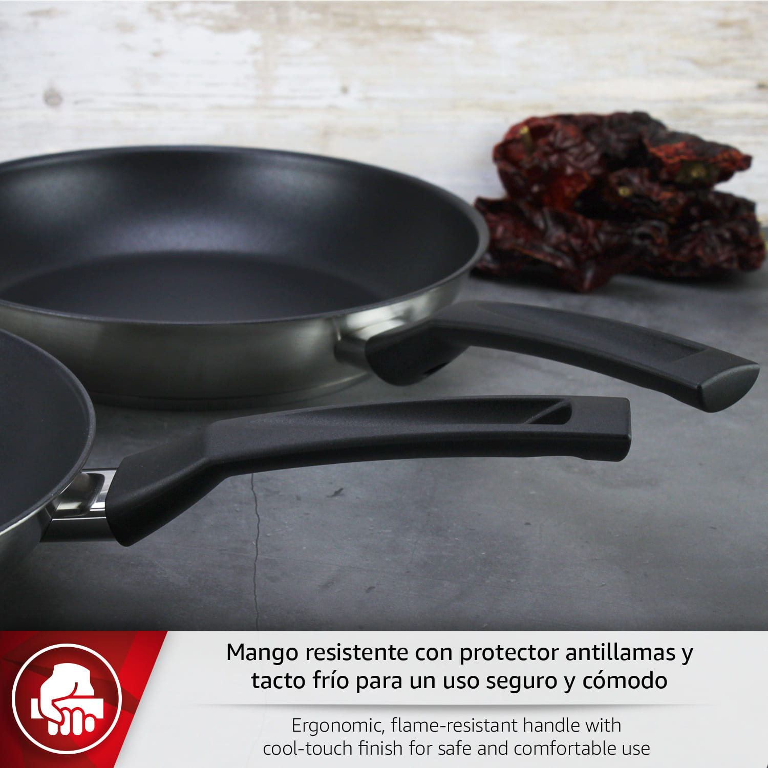 Dos sartenes con mangos negros y chiles rojos al fondo.