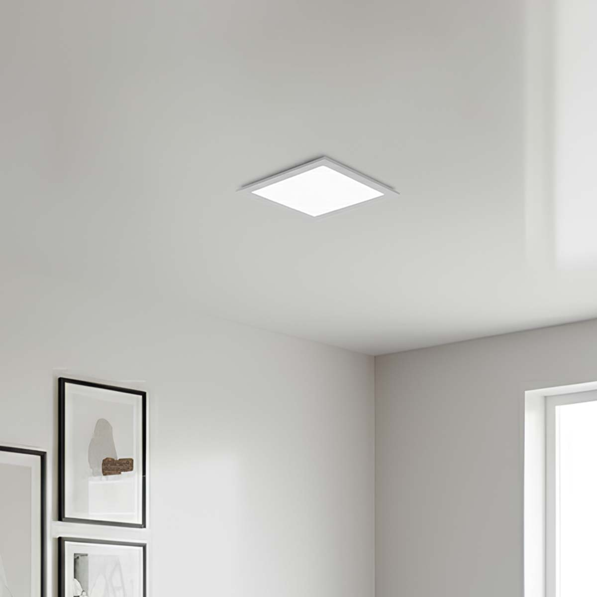Una lámpara cuadrada en el techo ilumina una sala con cuadros.
