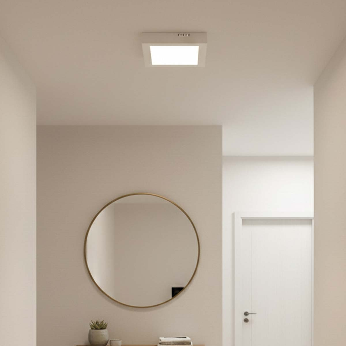 Un pasillo moderno con espejo redondo, lámpara y puerta blanca.