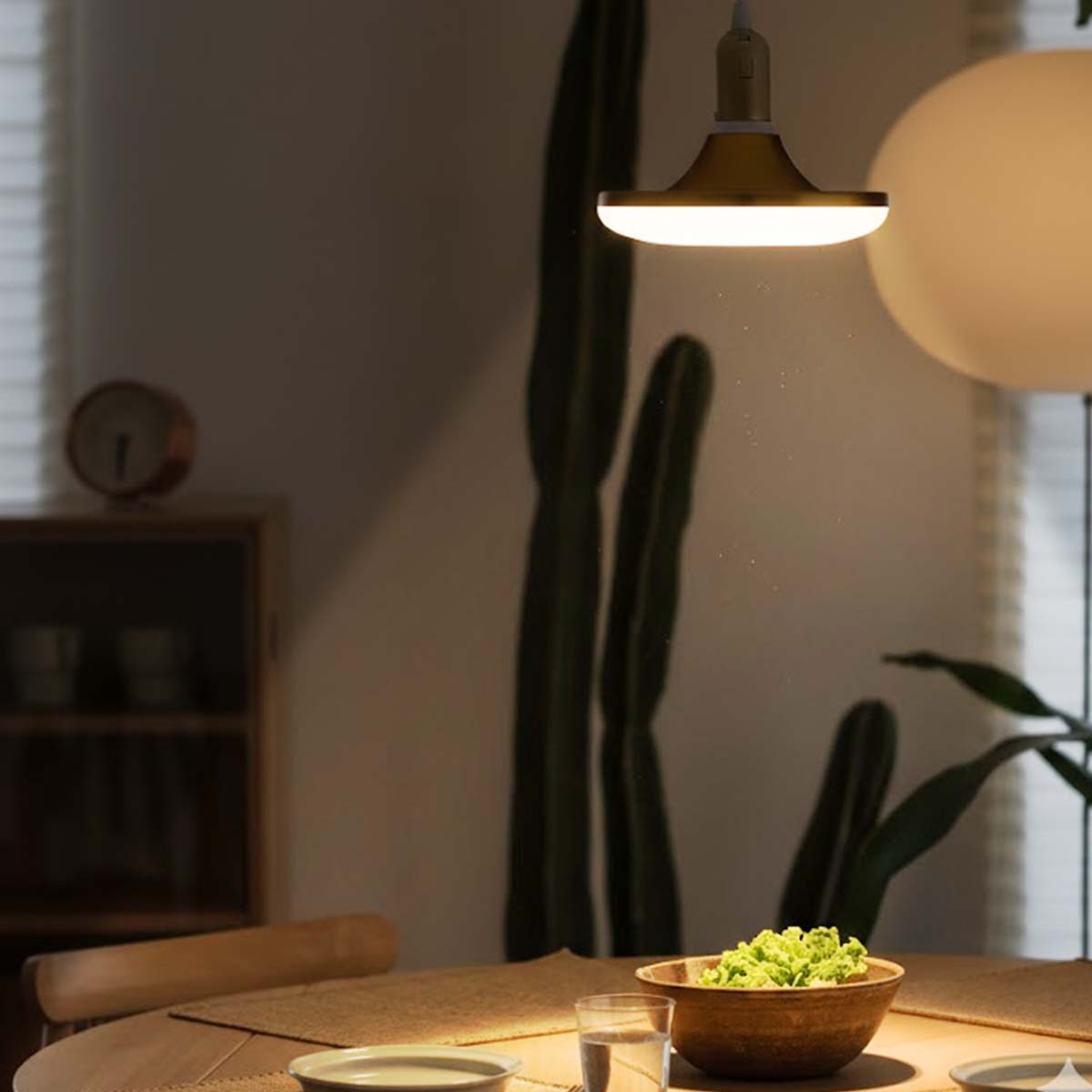 Una mesa de comedor con un cuenco de comida verde, un vaso de agua y velas.